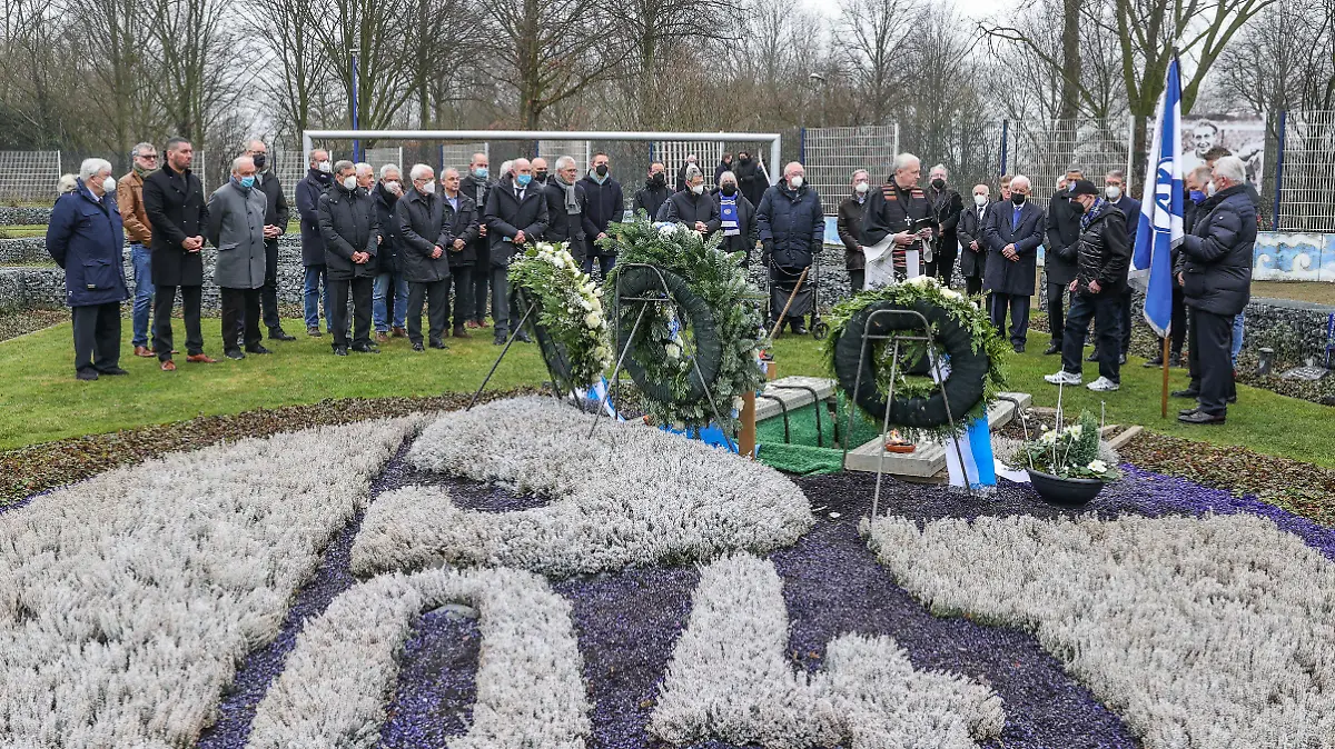 dpatopbilder - 15.01.2022, Nordrhein-Westfalen, Gelsenkirchen: Die Trauergemeinde steht am Grab von Reinhard Libuda. Nach dem Ende der Liegezeit von 25 Jahren erhält der frühere Schalker Stürmer Reinhard «Stan» Libuda nun doch eine neue letzte Ruhestätte auf dem Fan-Feld. Foto: Tim Rehbein/dpa +++ dpa-Bildfunk +++