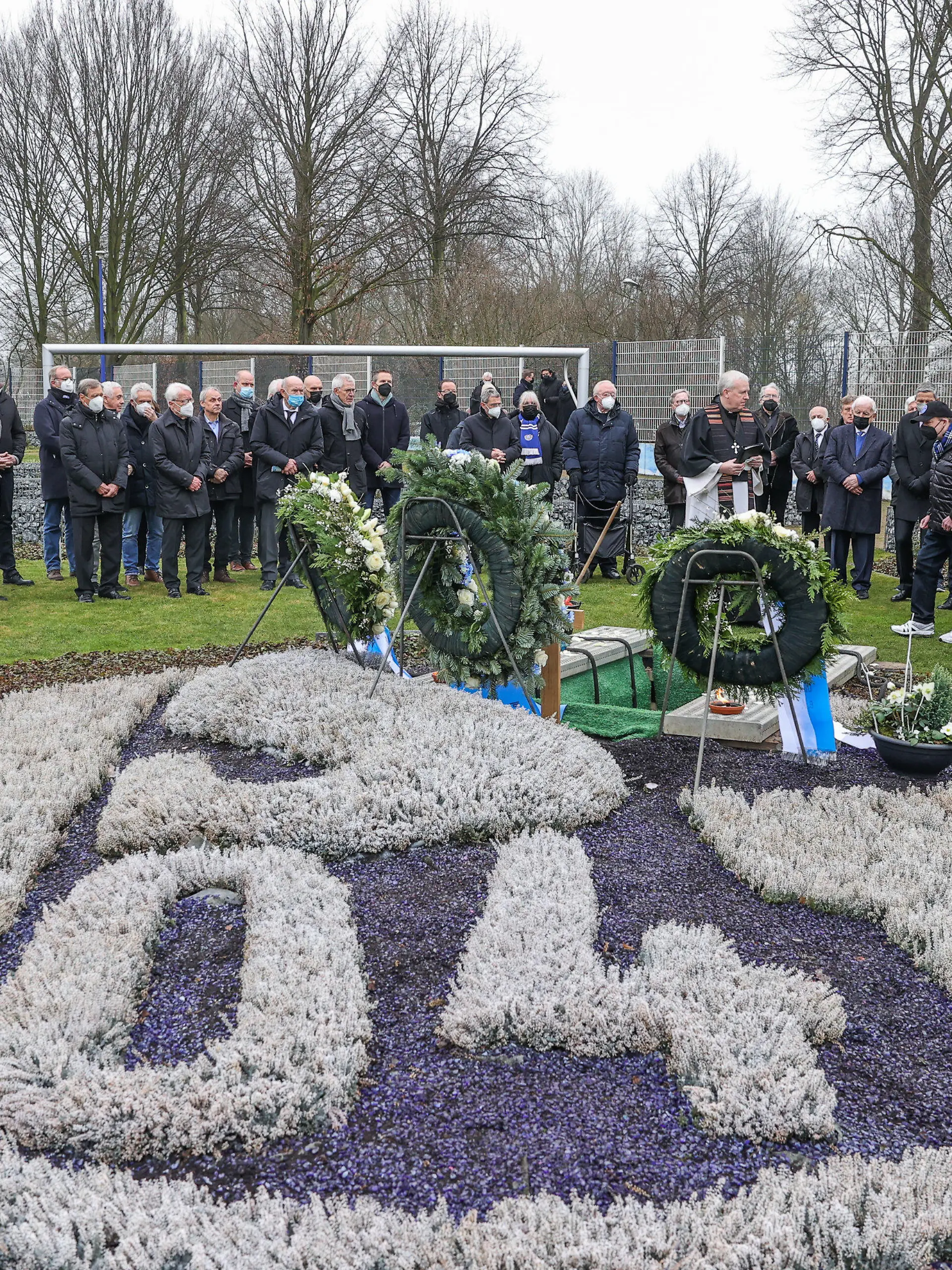 dpatopbilder - 15.01.2022, Nordrhein-Westfalen, Gelsenkirchen: Die Trauergemeinde steht am Grab von Reinhard Libuda. Nach dem Ende der Liegezeit von 25 Jahren erhält der frühere Schalker Stürmer Reinhard «Stan» Libuda nun doch eine neue letzte Ruhestätte auf dem Fan-Feld. Foto: Tim Rehbein/dpa +++ dpa-Bildfunk +++