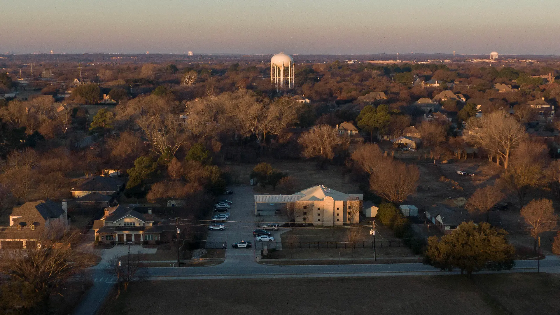 An aerial view of police standing in front of the Congregation Beth Israel synagogue, Sunday, Jan. 16, 2022, in Colleyville, Texas. A man held hostages for more than 10 hours Saturday inside the temple. The hostages were able to escape and the hostage taker was killed. FBI Special Agent in Charge Matt DeSarno said a team would investigate "the shooting incident." (AP Photo/Brandon Wade)