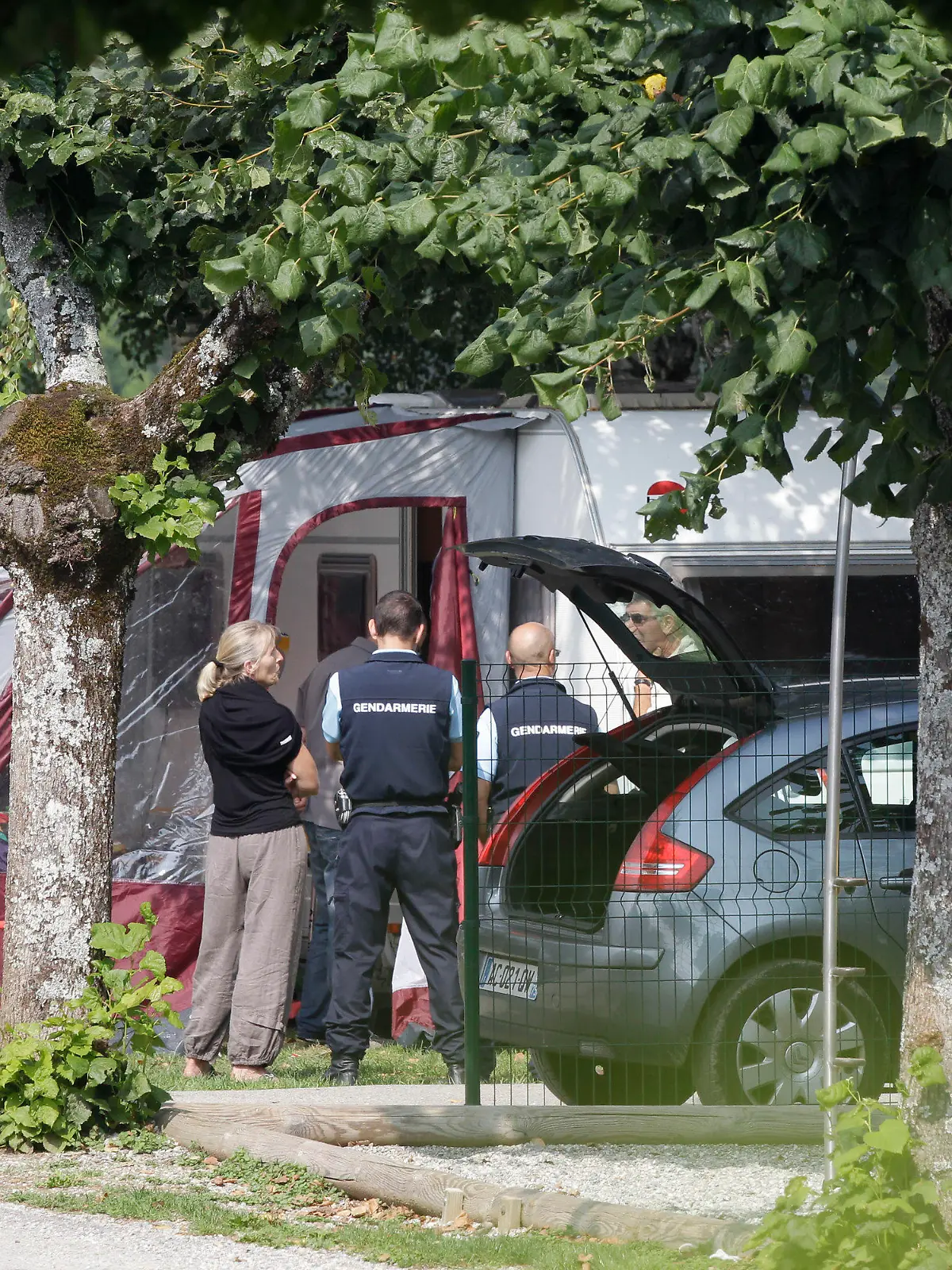 ARCHIV - 06.09.2012, Frankreich, Saint Jorioz: Ermittler und Gendamerie stehen vor dem Wohnwagen, in dem die Familienmitglieder auf einem Campingplatz in Saint Jorioz in der Nähe von Annecy in den französischen Alpen Urlaub machten. Mehr als neun Jahre nach einem mysteriösen Vierfachmord in den französischen Alpen haben Fahnder einen Verdächtigen festgenommen. Ein Unbekannter hatte dort im September 2012 ein irakischstämmiges Ehepaar und die Mutter der Ehefrau auf einem Waldparkplatz erschossen. Ebenfalls getötet wurde ein offensichtlich zufällig vorbeikommender Radfahrer. Nur die beiden Töchter des bei London lebenden Paares im Alter von vier und sieben Jahren überlebten. (zu dpa: «Festnahme nach Vierfachmord von 2012 in den französischen Alpen») Foto: Lionel Cironneau/AP/dpa +++ dpa-Bildfunk +++