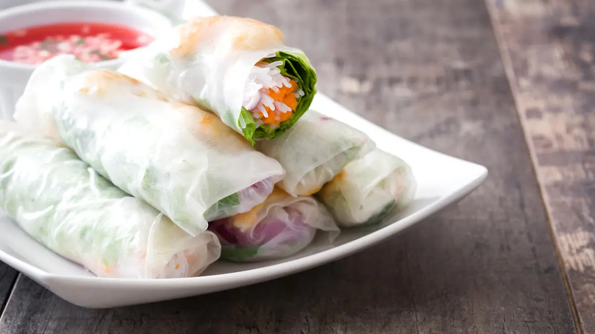 Vietnamese rolls with vegetables, rice noodles and prawns on wooden background