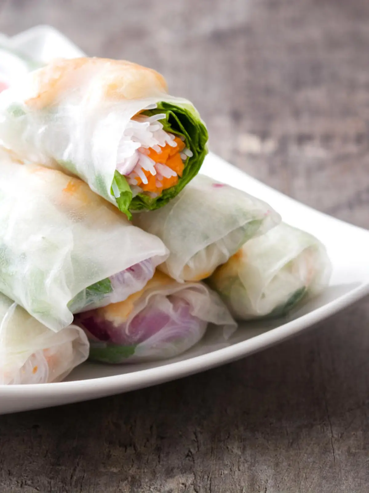 Vietnamese rolls with vegetables, rice noodles and prawns on wooden background