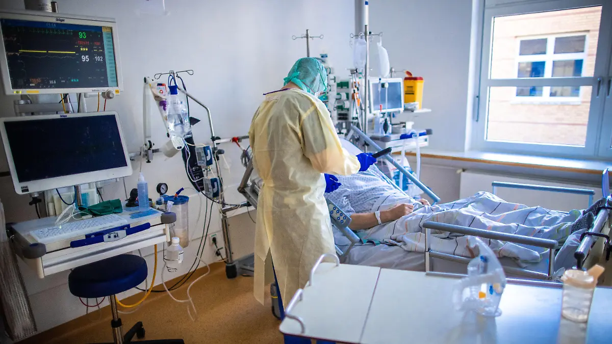 ARCHIV - 23.11.2020, Mecklenburg-Vorpommern, Greifswald: Eine Pflegekraft betreut im besonders geschützten Teil der Intensivstation des Universitätsklinikums Greifswald einen Corona-Patienten. Die Zahl der Todesfälle und der Neuinfektionen mit dem Coronavirus bleibt auf hohem Niveau. Die deutschen Gesundheitsämter haben dem Robert Koch-Institut (RKI) 19 528 neue Fälle und 731 Todesfälle binnen eines Tages übermittelt, wie das RKI am Dienstag (22.12.2020) bekanntgab. Foto: Jens Büttner/dpa-Zentralbild/dpa +++ dpa-Bildfunk +++