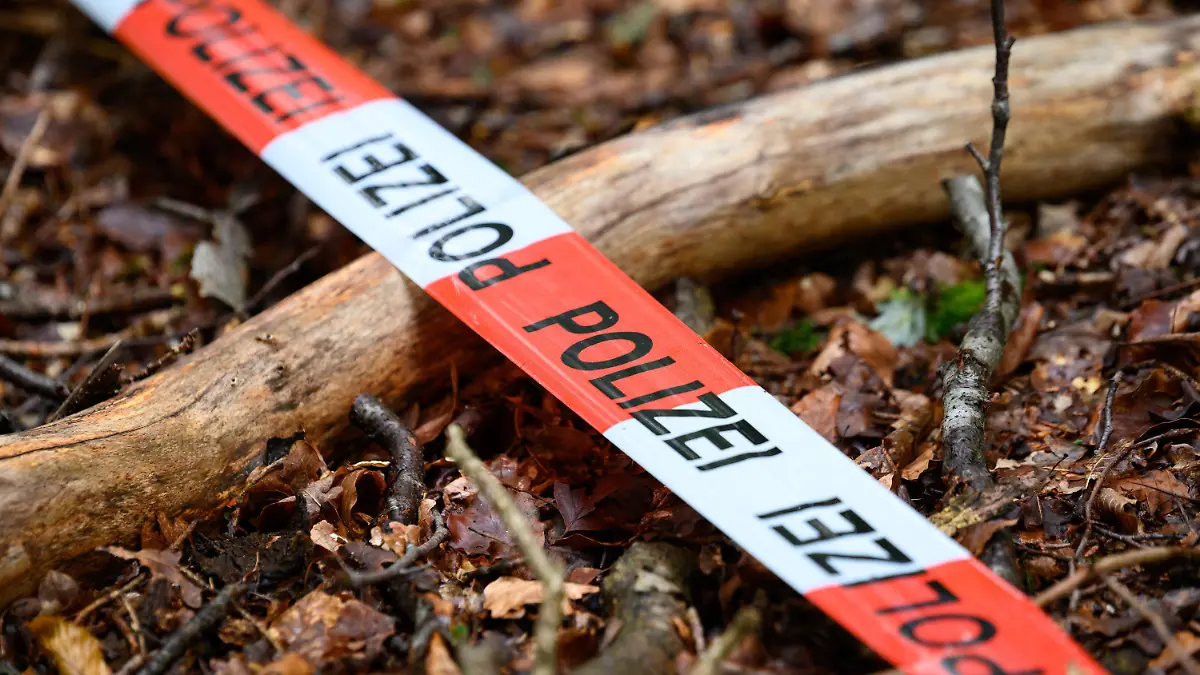 ARCHIV - 26.07.2022, Schleswig-Holstein, Norderstedt: Ein Flatterband der Polizei ist zur Markierung über den Waldboden gespannt. (Illustration zu dpa "Vermisste Mutter tot - Tatverdächtiger in Haft") Foto: Jonas Walzberg/dpa +++ dpa-Bildfunk +++