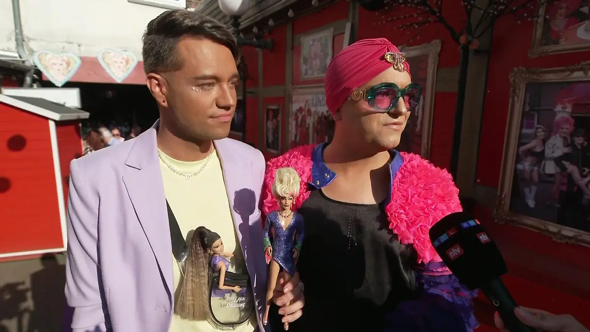 Statt Blumen oder Getränken haben Julian F.M. Stöckel und sein Partner eine personalisierte Puppe dabei.