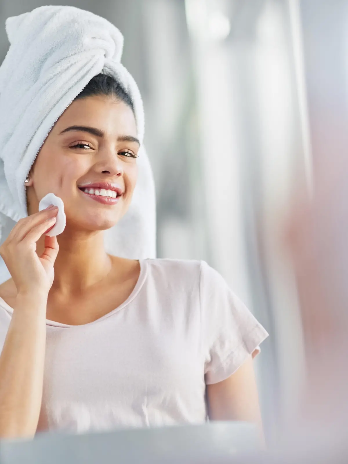 Shot of a beautiful young woman cleaning her face with cotton wool in the bathroom at home