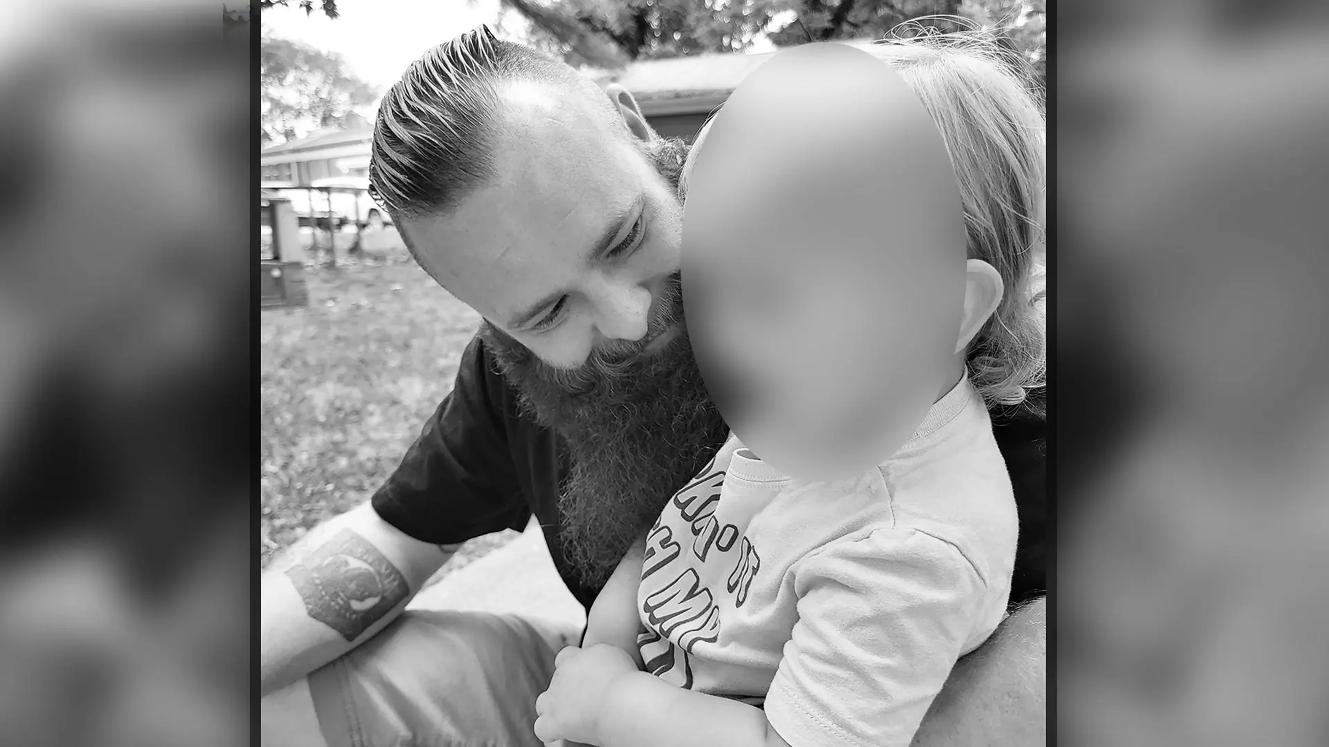 Schwarz-Weiß-Foto eines Vaters mit seinem Sohn auf dem Schoß