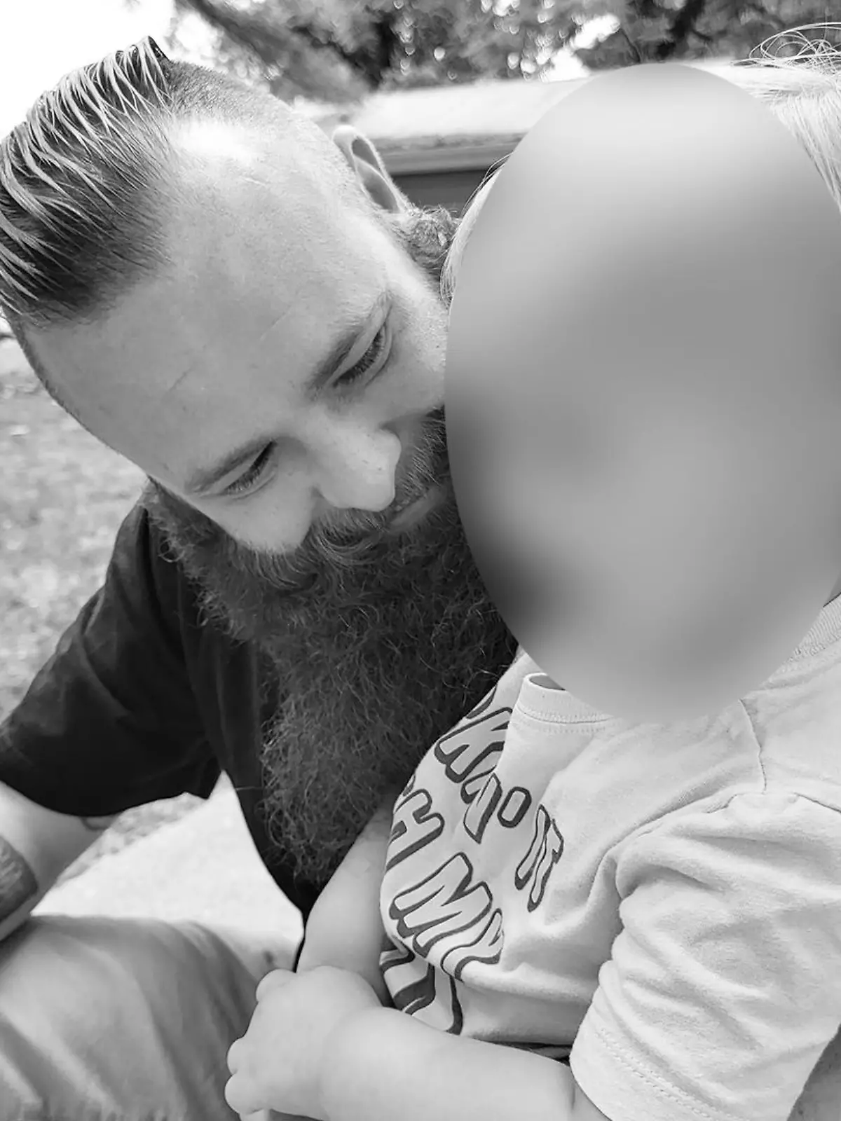 Schwarz-Weiß-Foto eines Vaters mit seinem Sohn auf dem Schoß