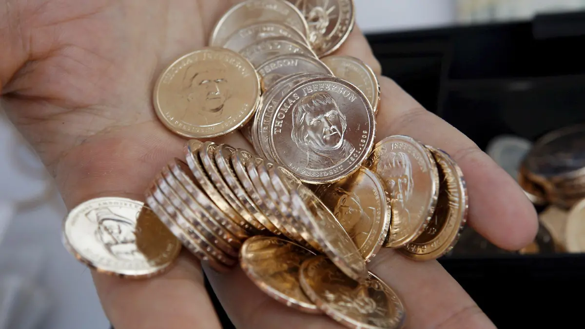 A cashier holds a handful of Thomas Jefferson dollar coins is during the release celebration of the New Thomas Jefferson one dollar coin at the Jefferson Memorial in Washington, D.C. USA 15 August 2007. The Jefferson dollar follows the Washington coin, which was introduced in February, and the John Adams coin, introduced in May. The coin honoring James Madison will go into circulation in November, and four more of the nation's presidents will be honored every year in the order they served in the White House. EPA/SHAWN THEW +++(c) dpa - Bildfunk+++