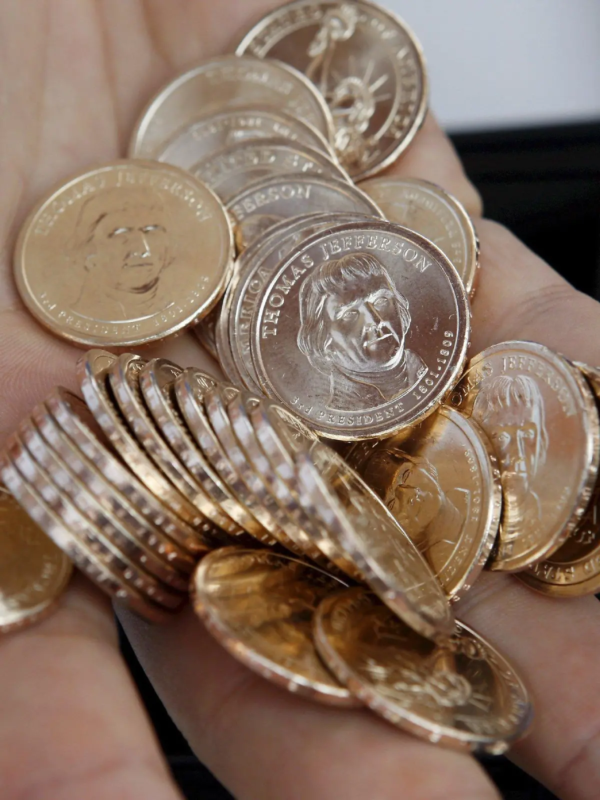 A cashier holds a handful of Thomas Jefferson dollar coins is during the release celebration of the New Thomas Jefferson one dollar coin at the Jefferson Memorial in Washington, D.C. USA 15 August 2007. The Jefferson dollar follows the Washington coin, which was introduced in February, and the John Adams coin, introduced in May. The coin honoring James Madison will go into circulation in November, and four more of the nation's presidents will be honored every year in the order they served in the White House. EPA/SHAWN THEW +++(c) dpa - Bildfunk+++
