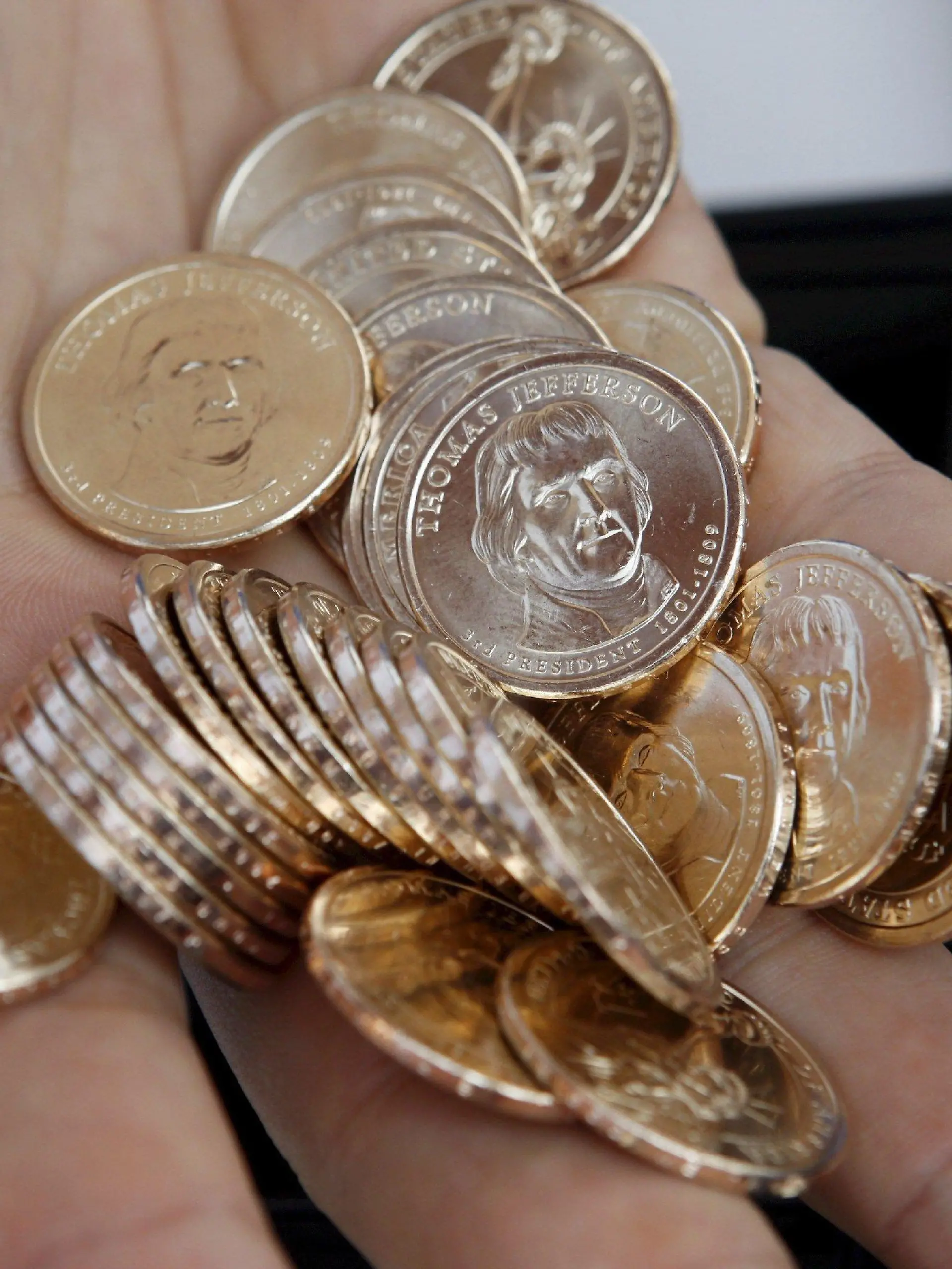 A cashier holds a handful of Thomas Jefferson dollar coins is during the release celebration of the New Thomas Jefferson one dollar coin at the Jefferson Memorial in Washington, D.C. USA 15 August 2007. The Jefferson dollar follows the Washington coin, which was introduced in February, and the John Adams coin, introduced in May. The coin honoring James Madison will go into circulation in November, and four more of the nation's presidents will be honored every year in the order they served in the White House. EPA/SHAWN THEW +++(c) dpa - Bildfunk+++