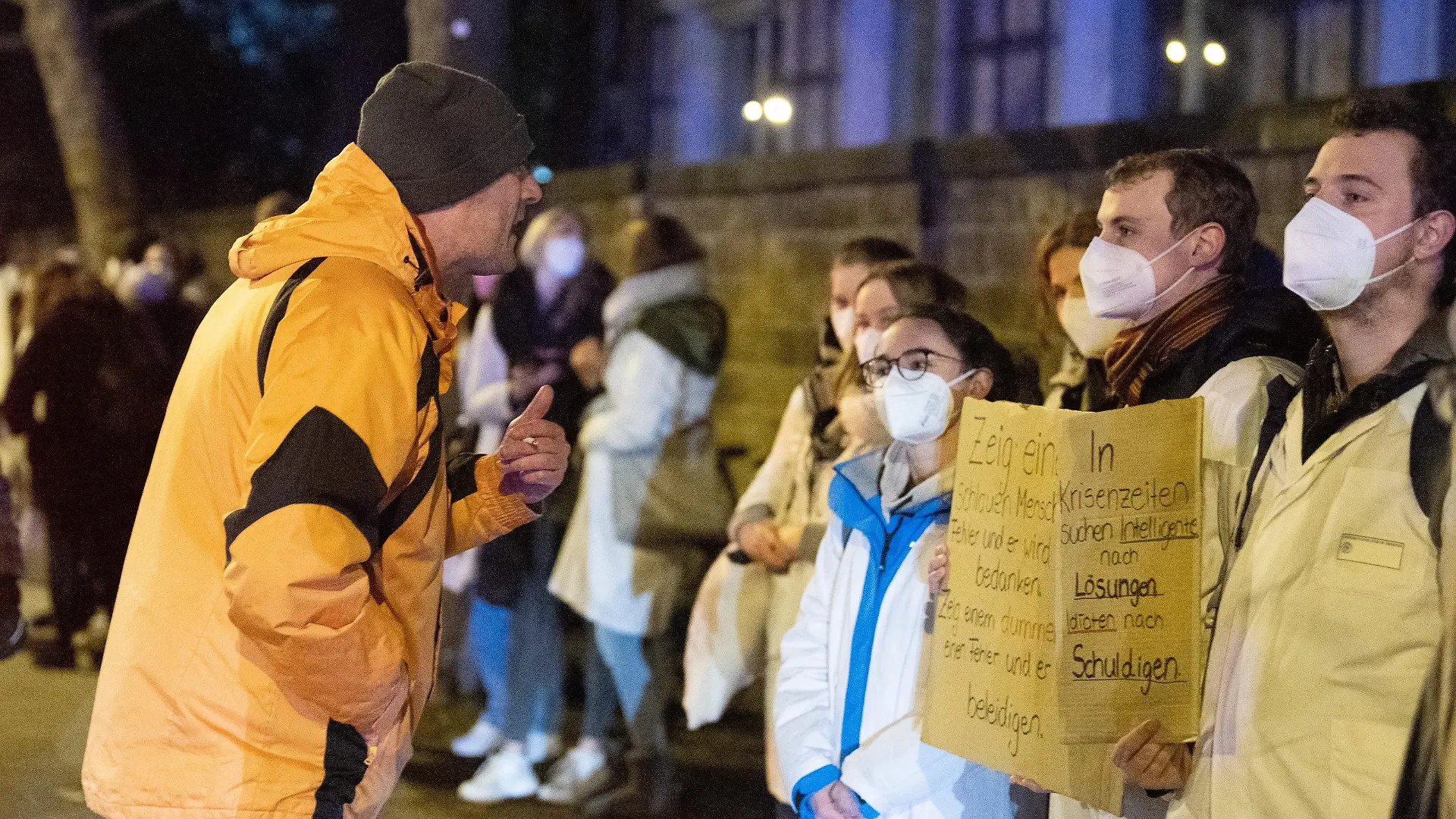 Ein Teilnehmer (l) einer als «Spaziergang» deklarierten Demonstration von Impfgegnern und Kritikern der Corona-Maßnahmen steht vor dem Universitätsklinikum Dresden vor zahlreichen Gegendemonstranten.