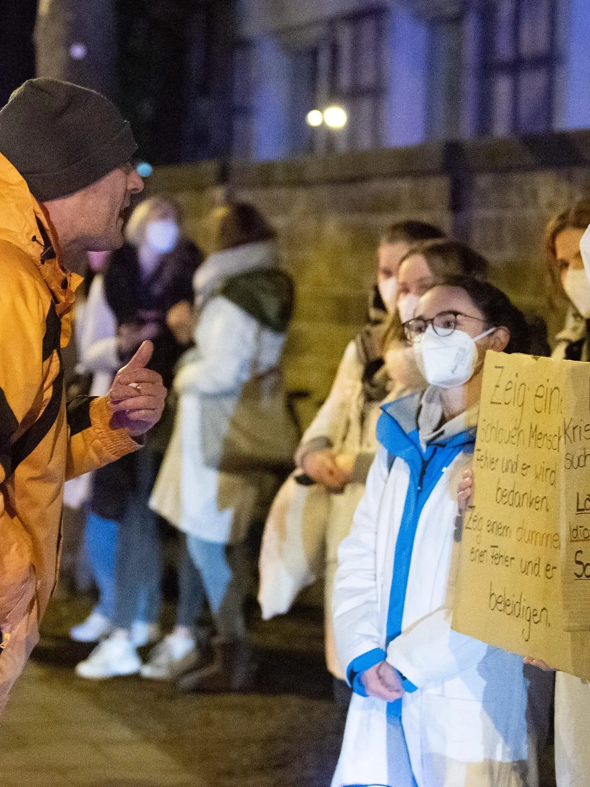 Ein Teilnehmer (l) einer als «Spaziergang» deklarierten Demonstration von Impfgegnern und Kritikern der Corona-Maßnahmen steht vor dem Universitätsklinikum Dresden vor zahlreichen Gegendemonstranten.