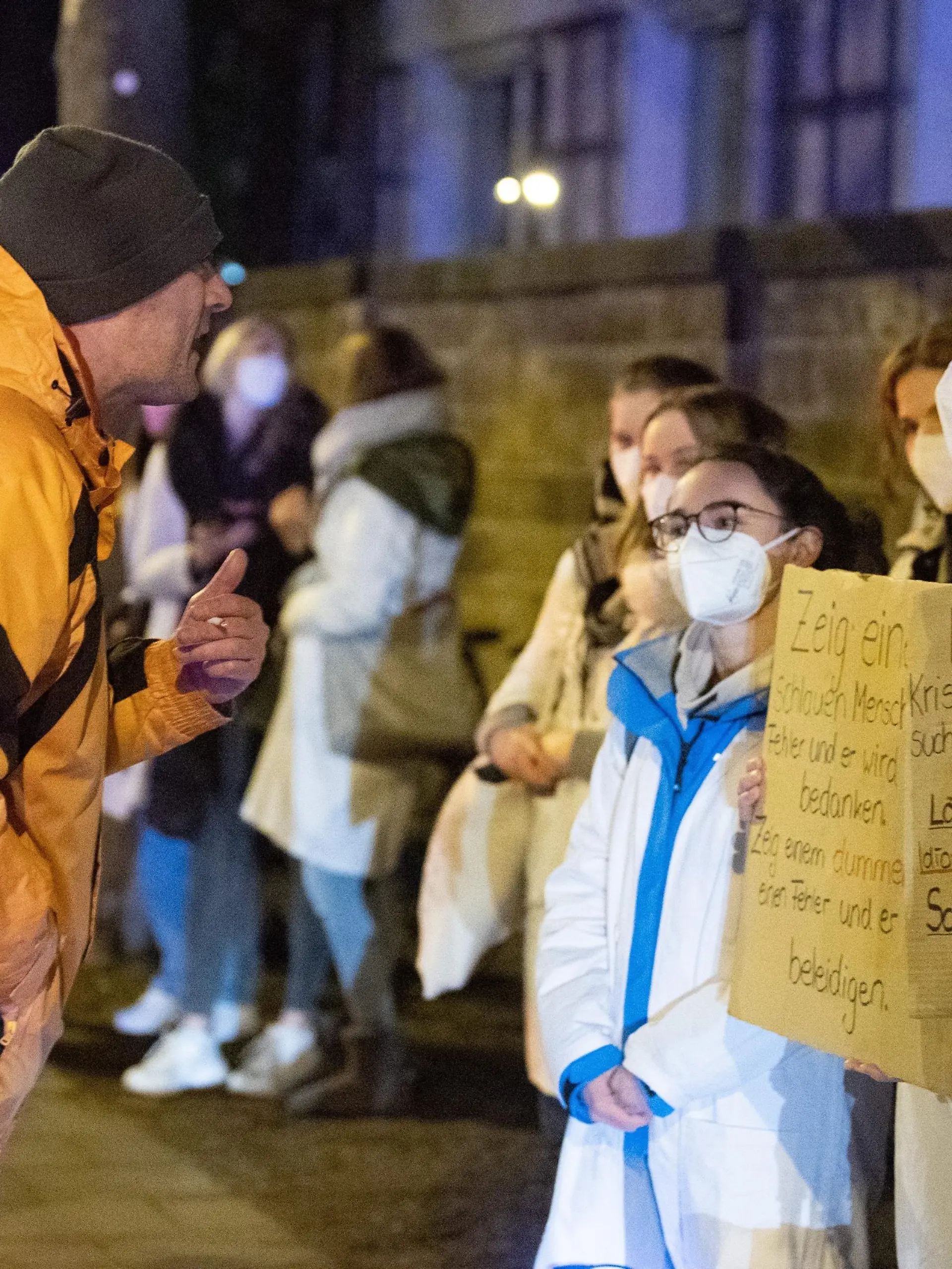 Ein Teilnehmer (l) einer als «Spaziergang» deklarierten Demonstration von Impfgegnern und Kritikern der Corona-Maßnahmen steht vor dem Universitätsklinikum Dresden vor zahlreichen Gegendemonstranten.