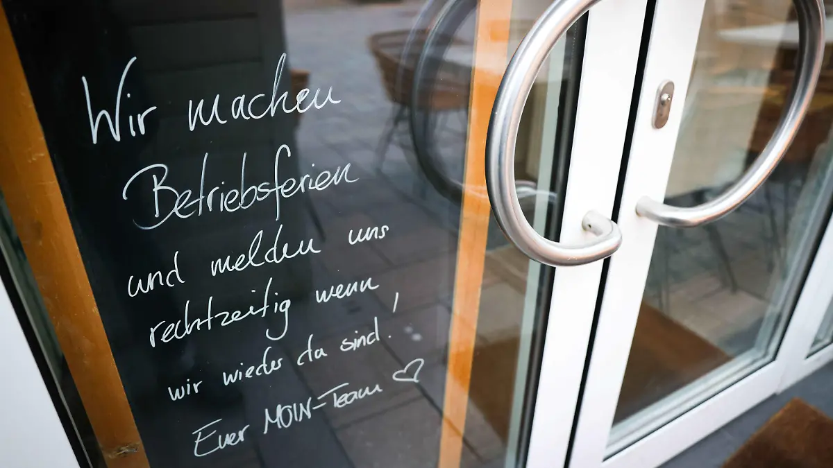 11.01.2022, Schleswig-Holstein, Westerland: Auf einer Tafel hinter der Eingangstür zu einem Restaurant in der Friedrichstraße steht «Wir machen Betriebsferien und melden uns rechtzeitig wenn wir wieder da sind!». Mehrere Hotels und Gaststätten auf Sylt haben angesichts der rasant steigenden Corona-Zahlen auf der Insel vorläufig geschlossen. Foto: Christian Charisius/dpa +++ dpa-Bildfunk +++