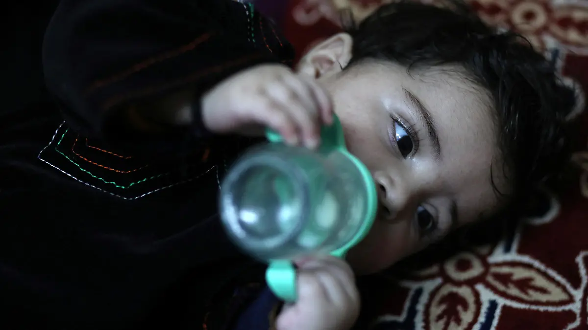 Baby Sohail Ahmadi drinks milk from a bottle inside the house of Hamid Safi, a taxi driver who had found Sohail in the airport, in Kabul, Afghanistan, January 7, 2022. Picture taken January 7, 2022. REUTERS/Ali Khara