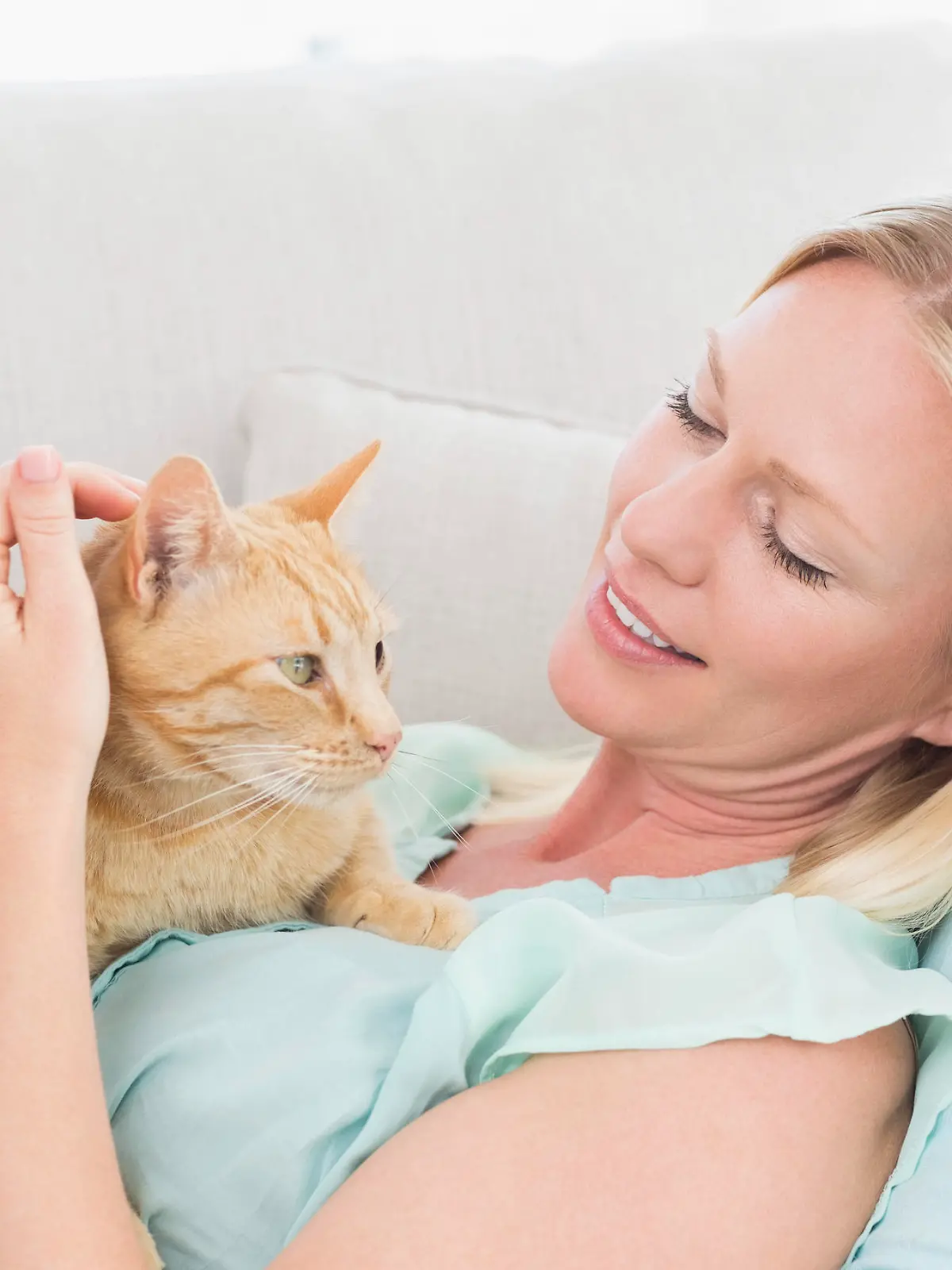 Young woman stroking cat while lying on sofa at home