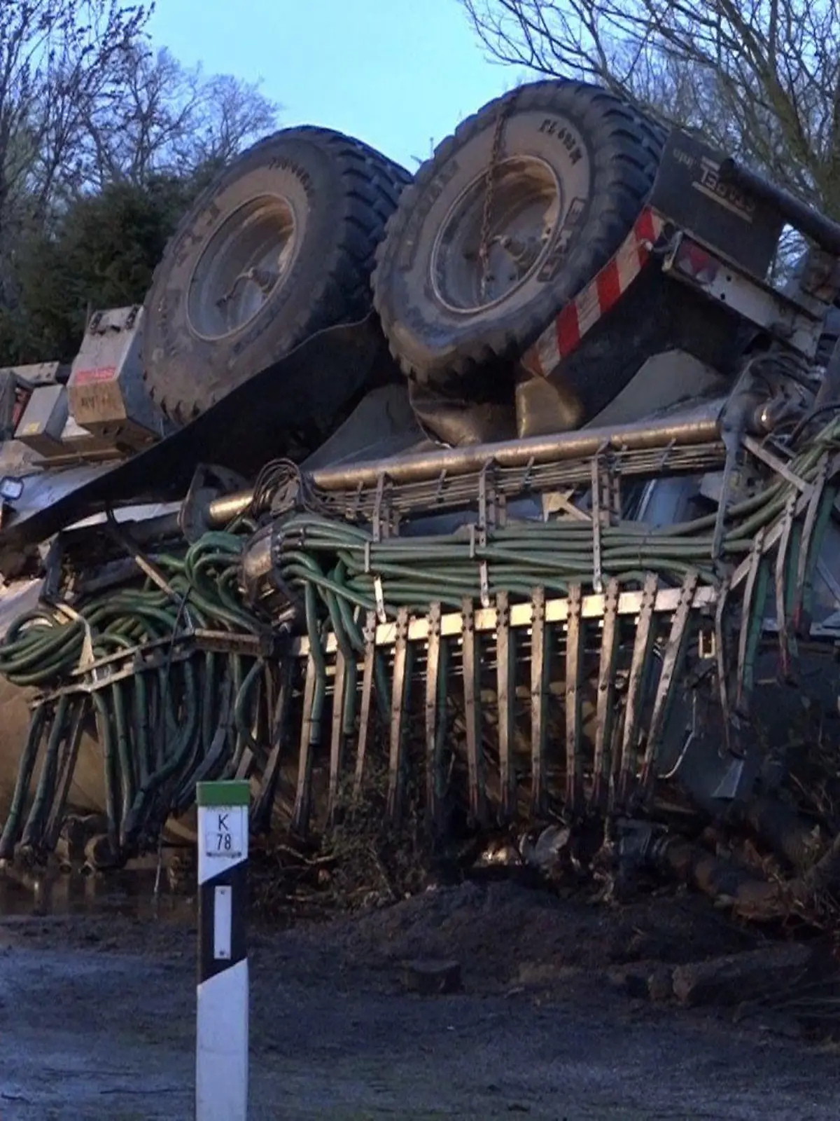 07.04.2021, Nordrhein-Westfalen, Horstmar: Nach einem Unfall liegt ein Trakor mit geladener Gülle auf dem Dach. Bildern zufolge ist der Anhänger des Traktors auf ein Carport gekippt und die Gülle ist ausgelaufen. Foto: Tebben/NWM-TV/dpa +++ dpa-Bildfunk +++