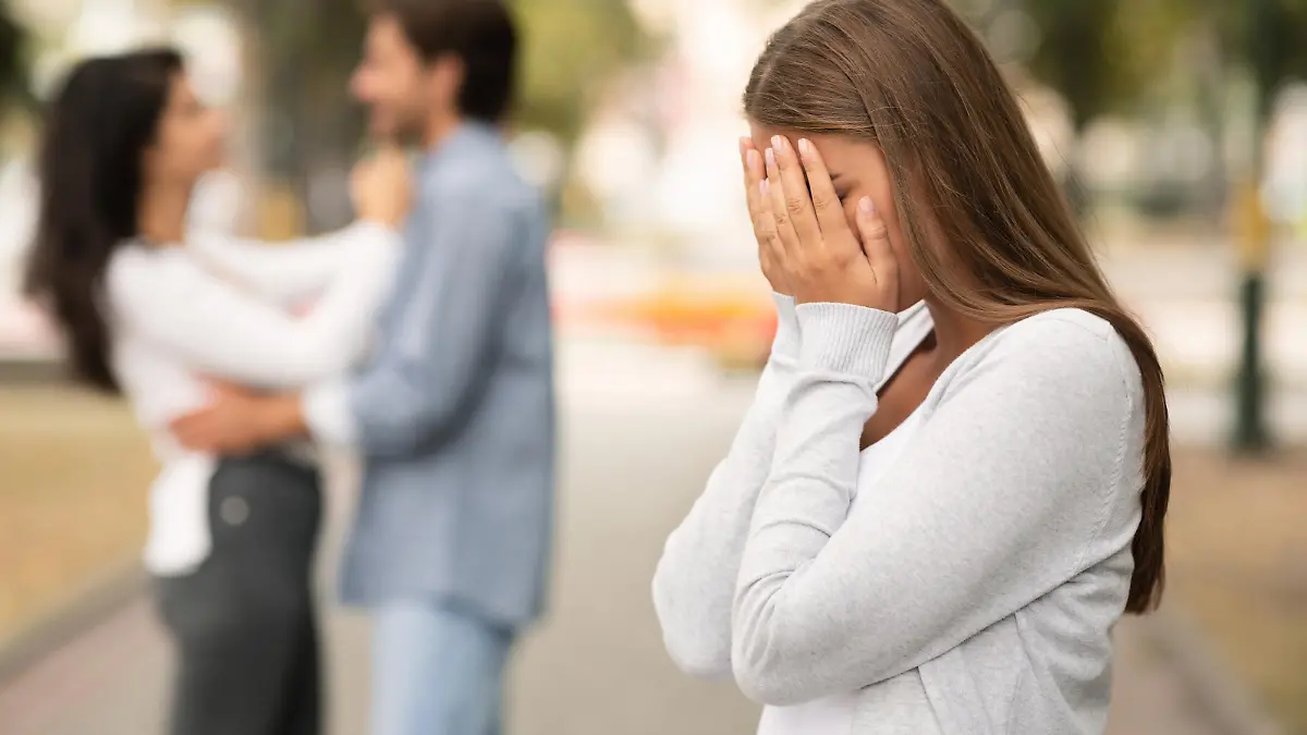 Upset woman crying, seeing her boyfriend with other girl in park