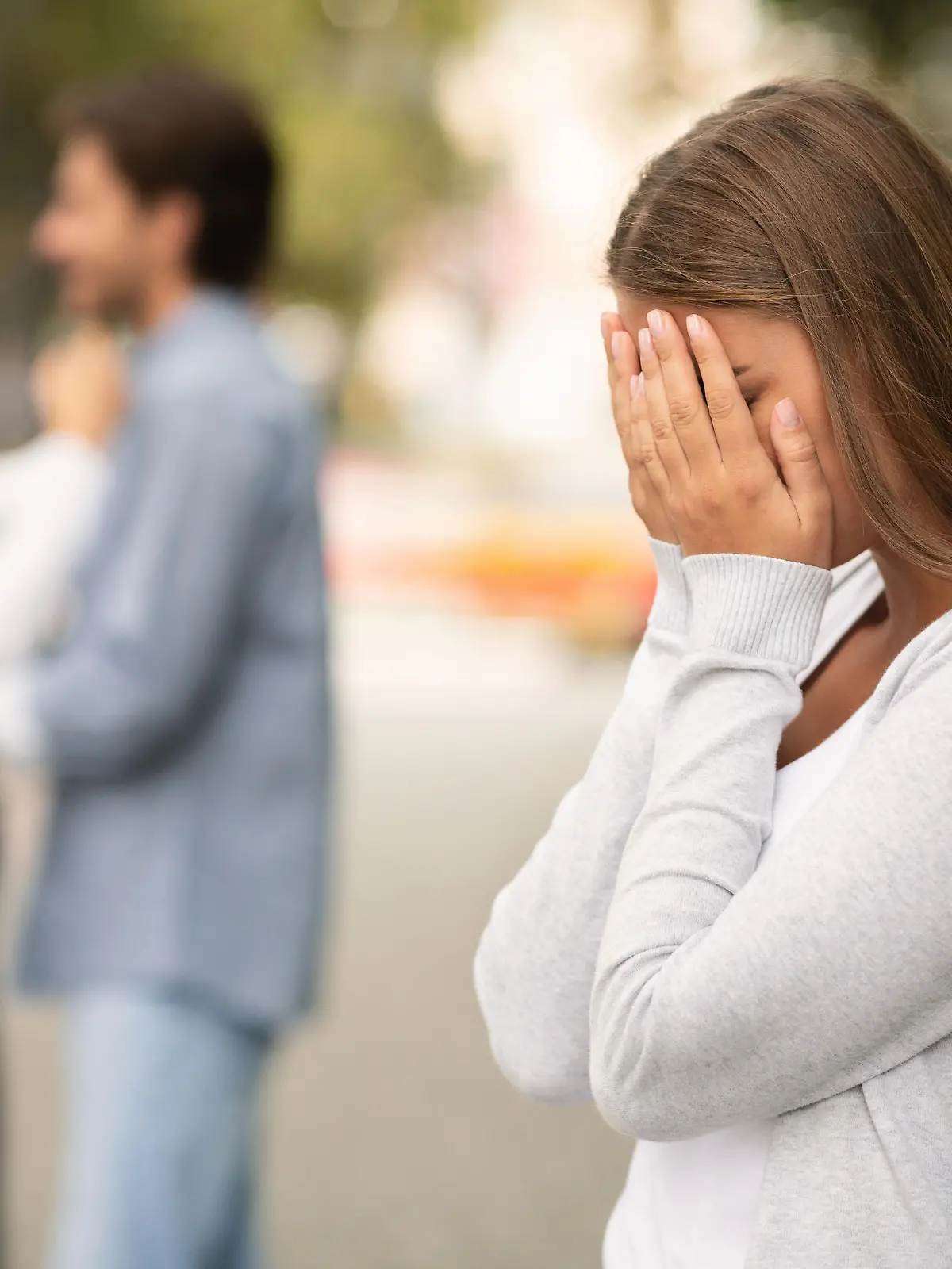 Upset woman crying, seeing her boyfriend with other girl in park