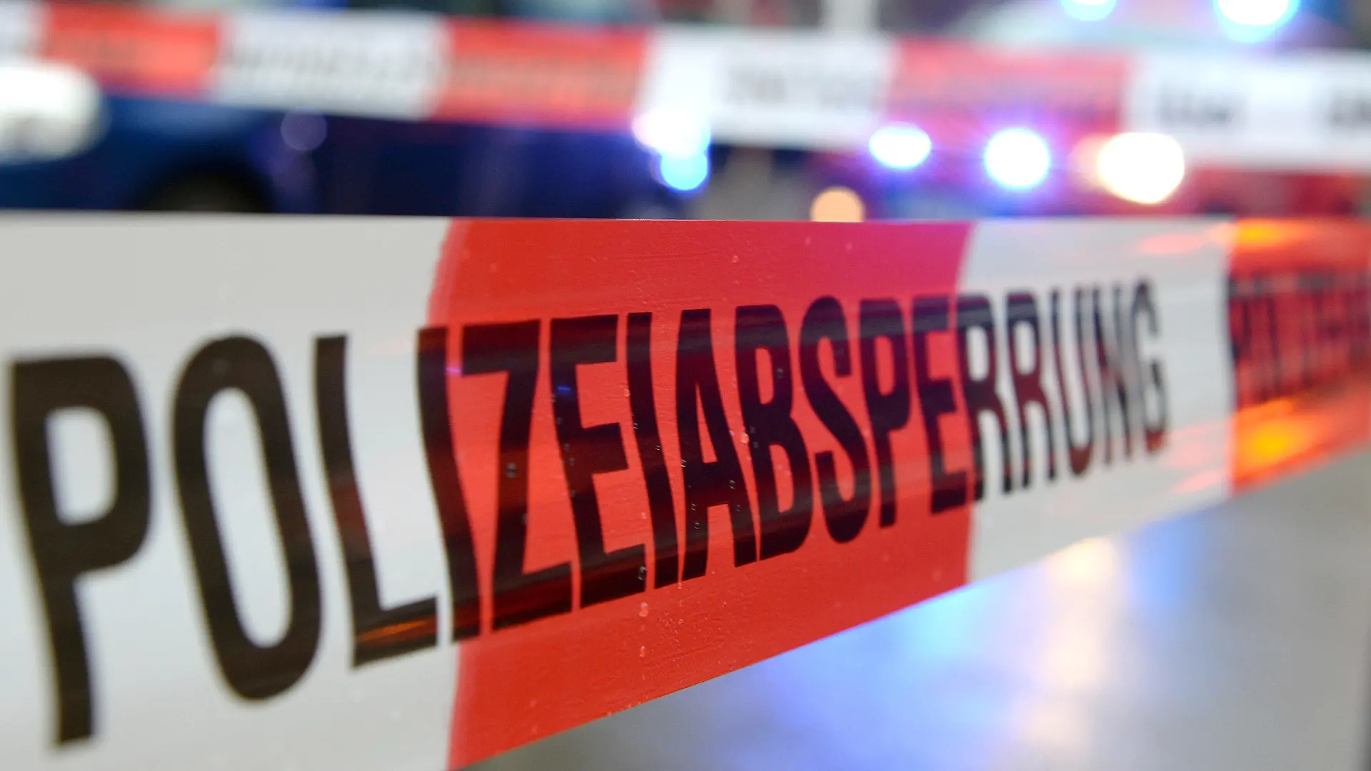 ARCHIV - Ein Flatterband mit der Aufschrift «Polizeiabsperrung» ist am 05.11.2014 in Freiburg (Baden-Württemberg) an einem Einsatzort vor einem Feuerwehrfahrzeug mit Blaulicht zu sehen (Illustration zum Thema Polizeiabsperrung). Mehrere Menschen sind in München (Bayern) von einem Unbekannten mit einem Messer angegriffen und verletzt worden. Foto: Patrick Seeger/dpa +++(c) dpa - Bildfunk+++