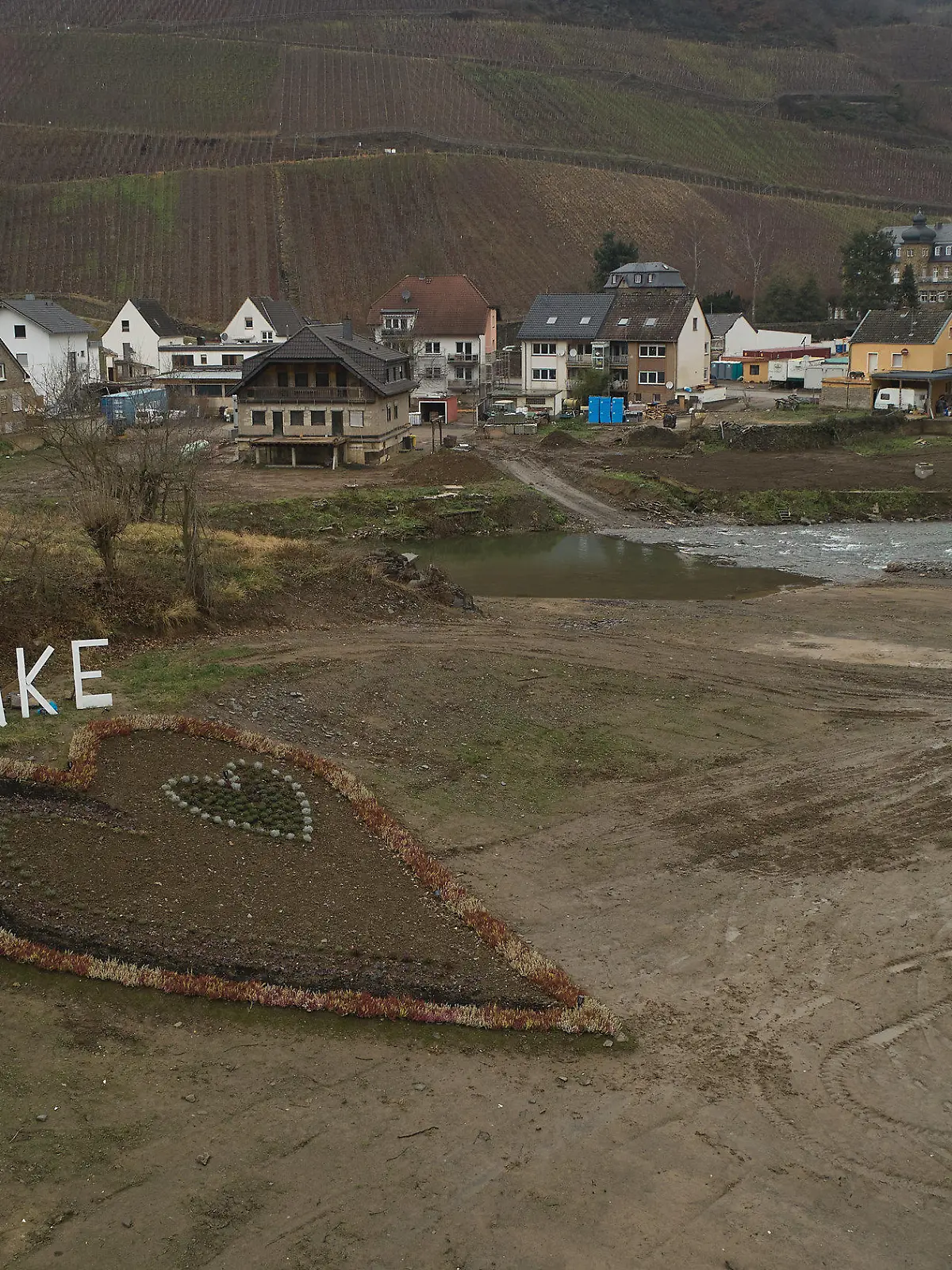 27.12.2021, Rheinland-Pfalz, Dernau: Mit einem herzförmigen Blumenbeet und einem Schriftzug "Danke" dahinter danken die Bewohner den Fluthelfern (Aufnahme mit einer Drohne). Fast ein halbes Jahr nach dem Hochwasser im Ahrtal müssen immer noch viele Flutopfer in Ausweichquartieren ausharren. (zu dpa-Korr "Hoffen auf Wiederaufbau - Ahrtal kämpft noch lange mit tödlicher Flut") Foto: Thomas Frey/dpa +++ dpa-Bildfunk +++