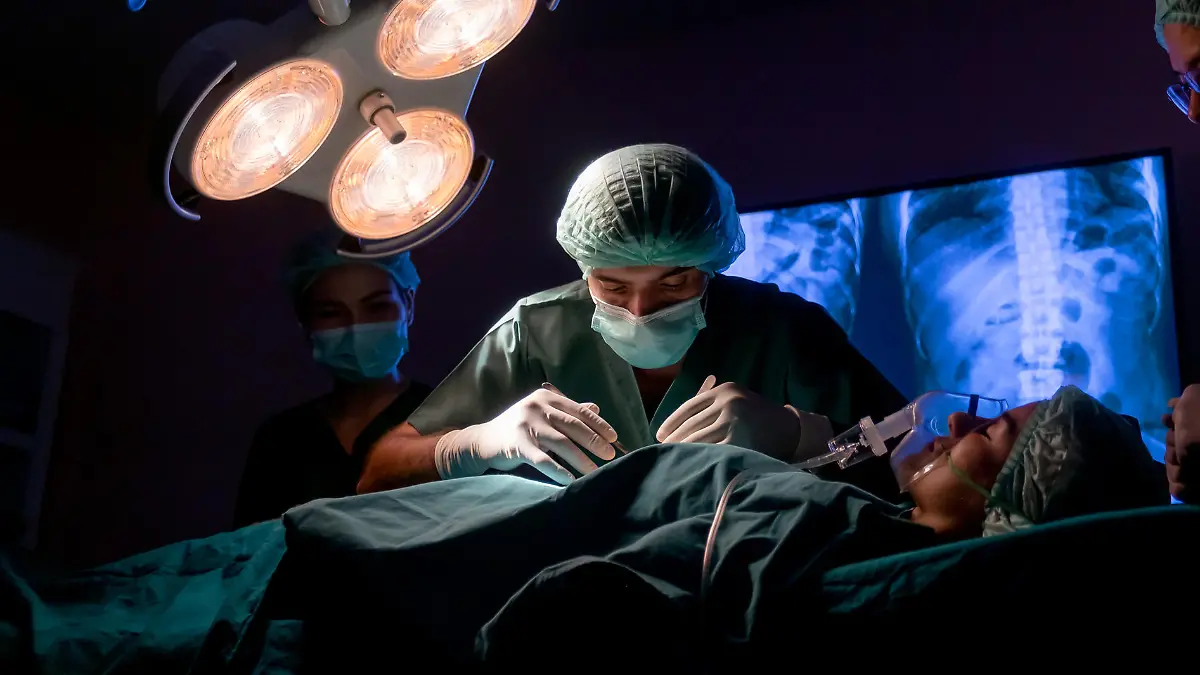 wide shot of operating doctor work on operation of patient with his staff stand to support near him in operating room of clinic or hospital.