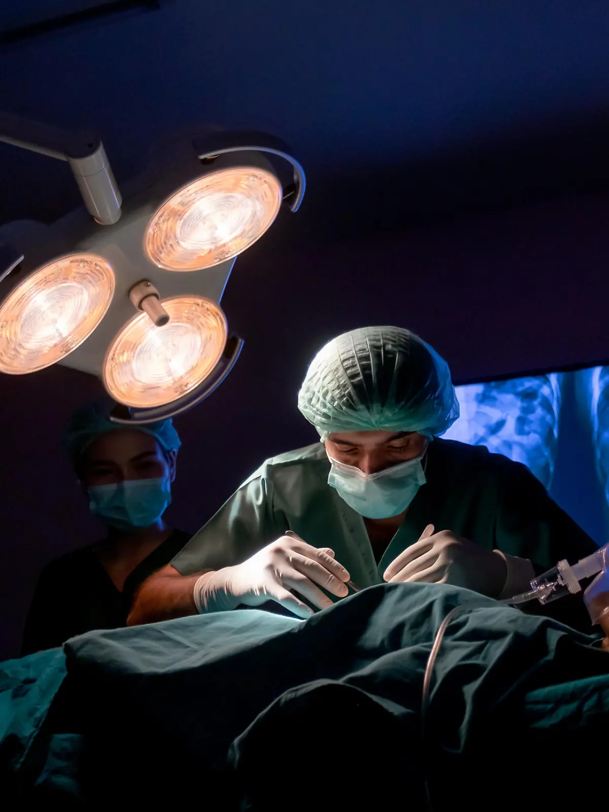 wide shot of operating doctor work on operation of patient with his staff stand to support near him in operating room of clinic or hospital.