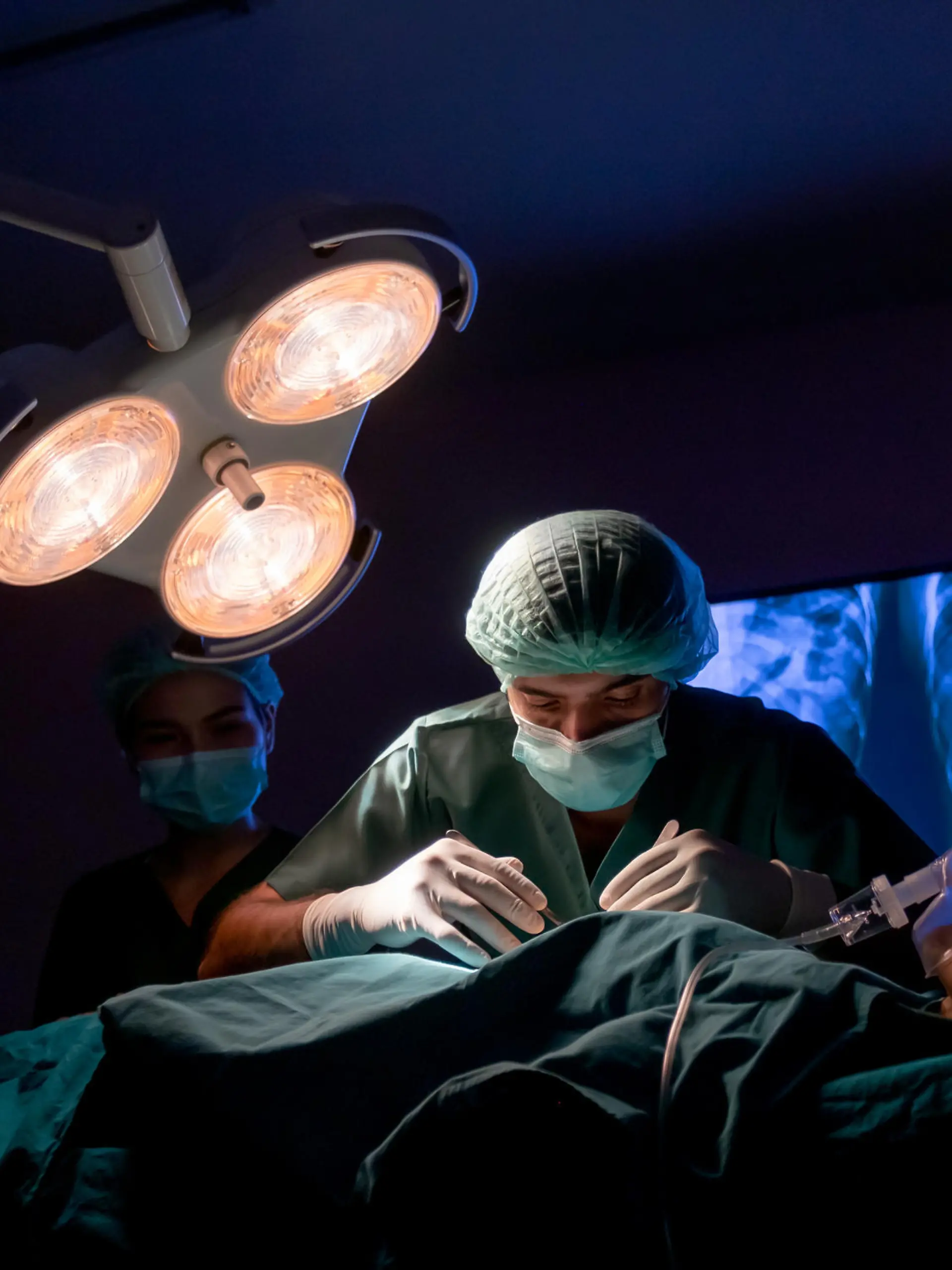 wide shot of operating doctor work on operation of patient with his staff stand to support near him in operating room of clinic or hospital.