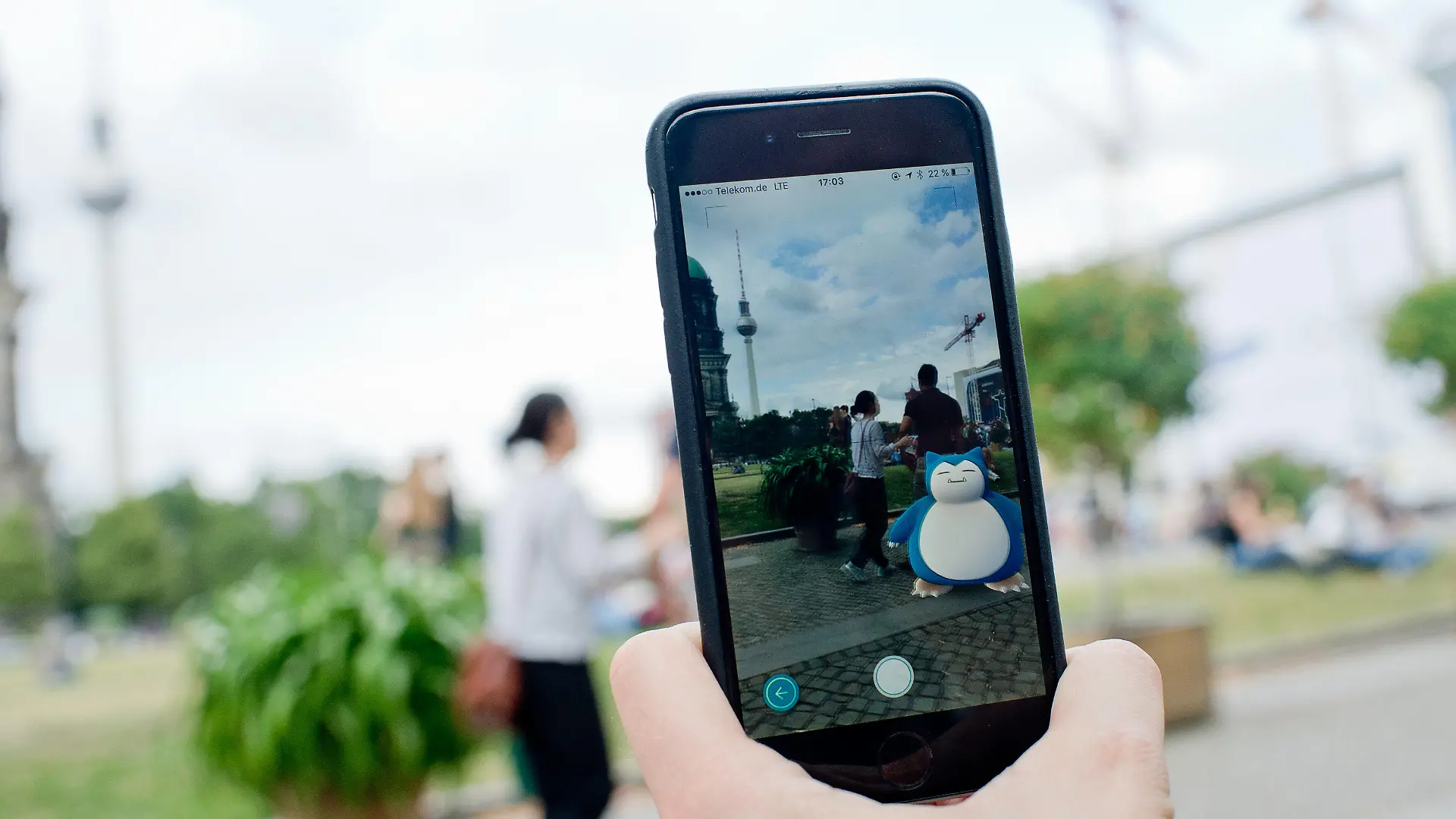 ILLUSTRATION - Ein «Pokémon Go» Spieler zeigt am 13.07.2016 in Berlin sein Smartphone, auf dem das Pokémon «Relaxo» zu sehen ist. Im Hintergrund der Berliner Fernsehturm. Das Spiel basiert auf echten Geodaten und führt seine Teilnehmer per GPS von Ort zu Ort. Foto: Henrik Josef Boerger/dpa (Zu dpa "Phänomen «Pokémon» - Wie kommt es zu dem Hype?" vom 14.07.2016) +++(c) dpa - Bildfunk+++
