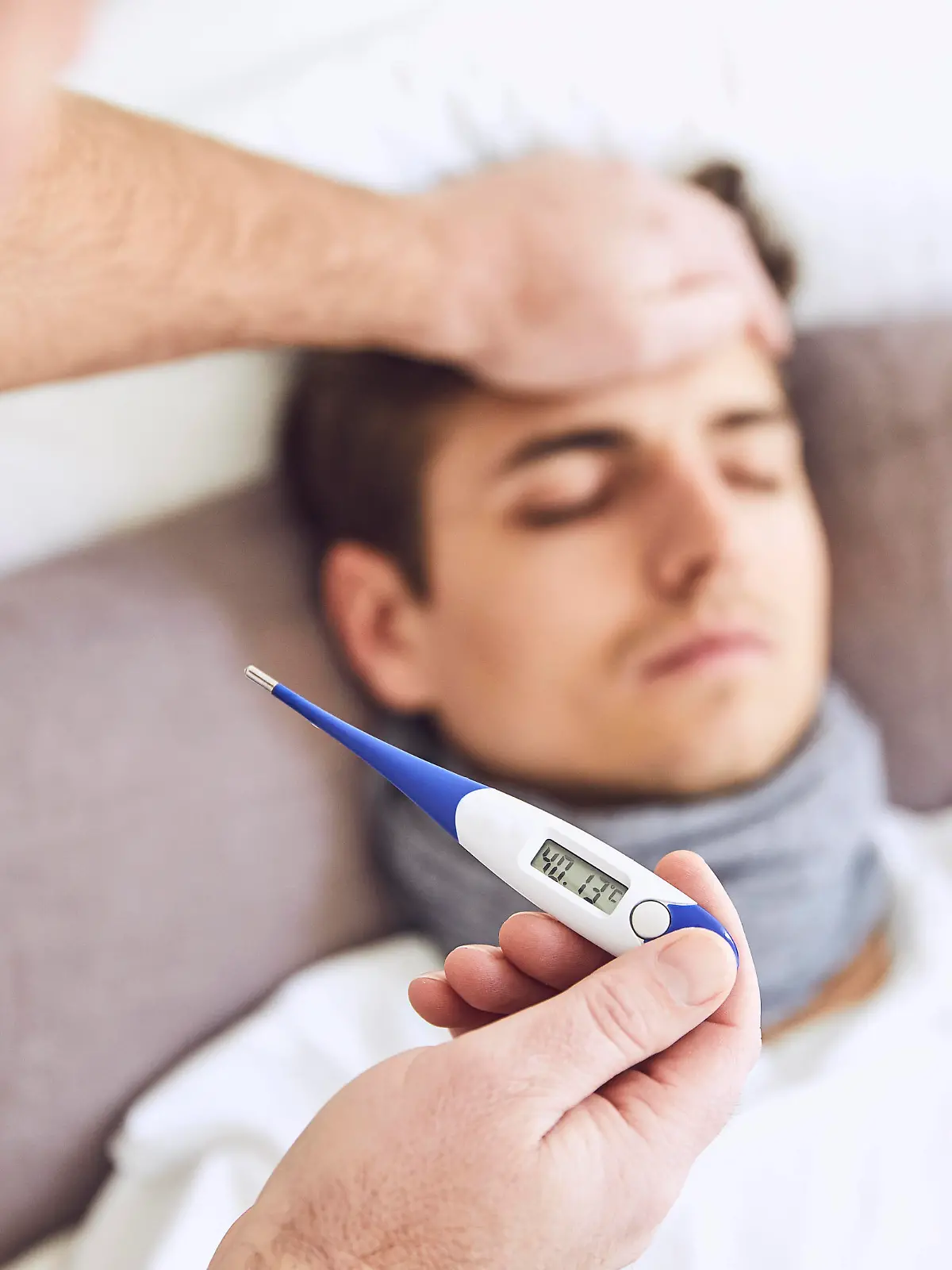  Close-up of doctor examining patient s temperature sleeping on bed at home model released Symbolfoto property released UKOF00029