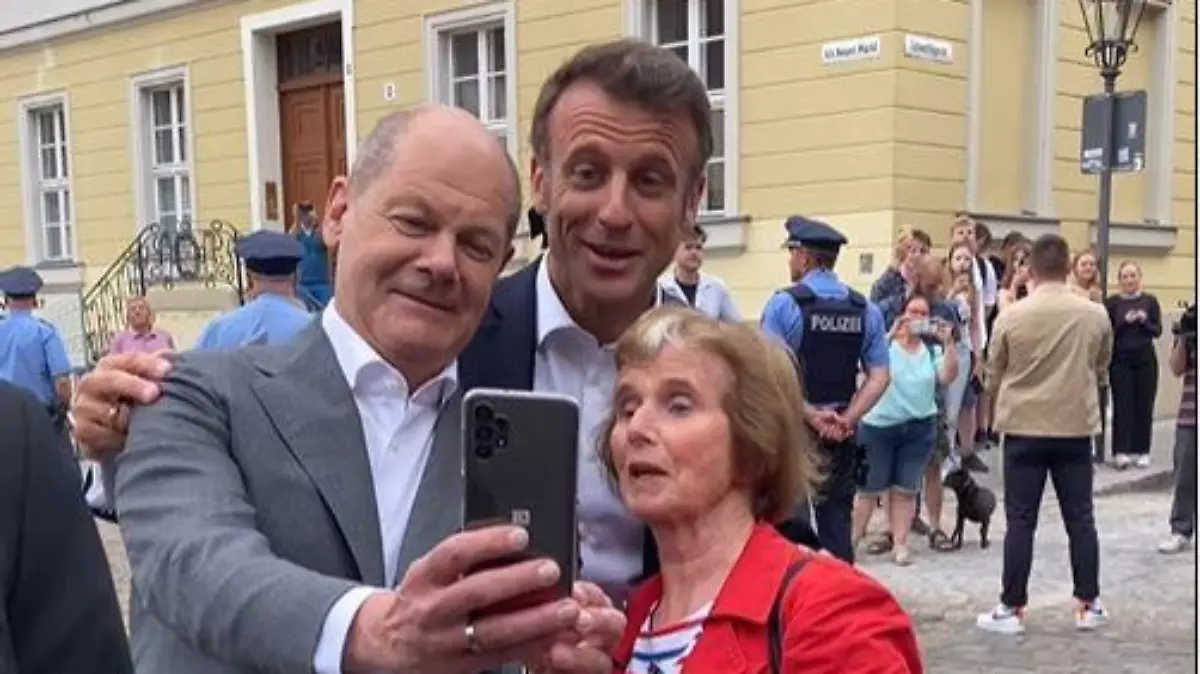 Olaf Scholz, Emmanuel Macron und die pensionierte Französisch-Lehrerin posieren für ein Foto.