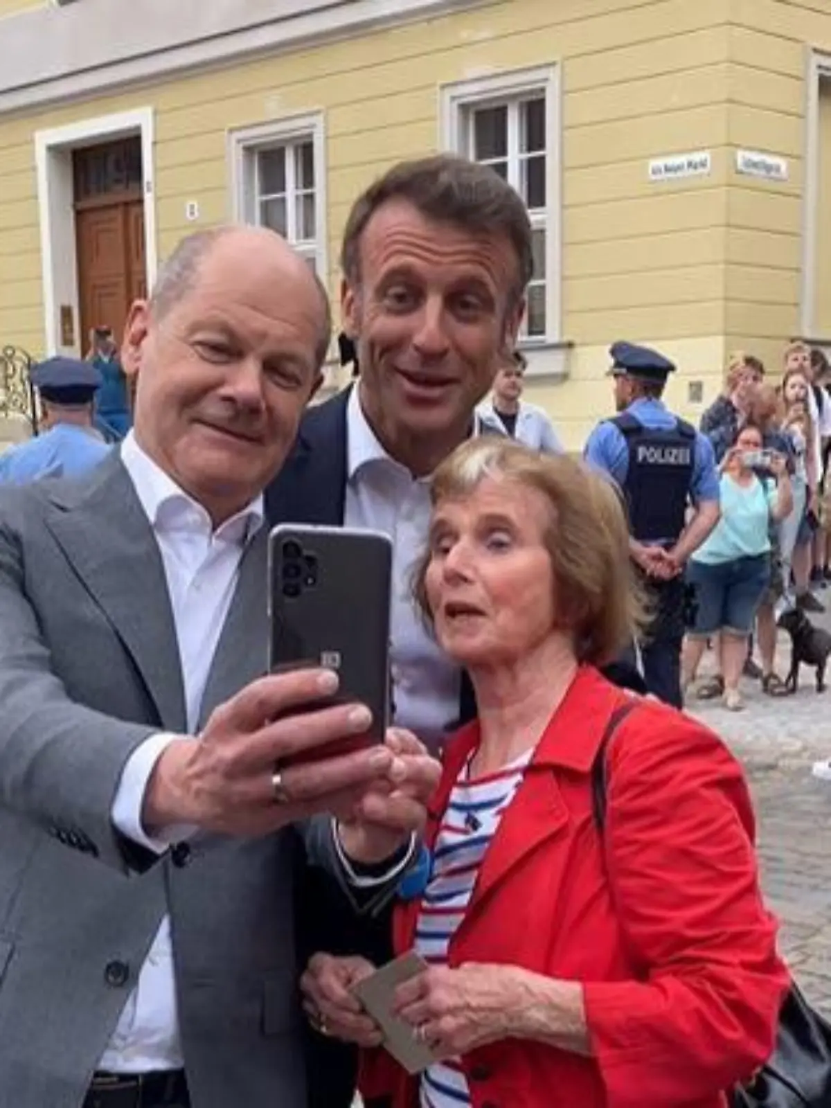 Olaf Scholz, Emmanuel Macron und die pensionierte Französisch-Lehrerin posieren für ein Foto.