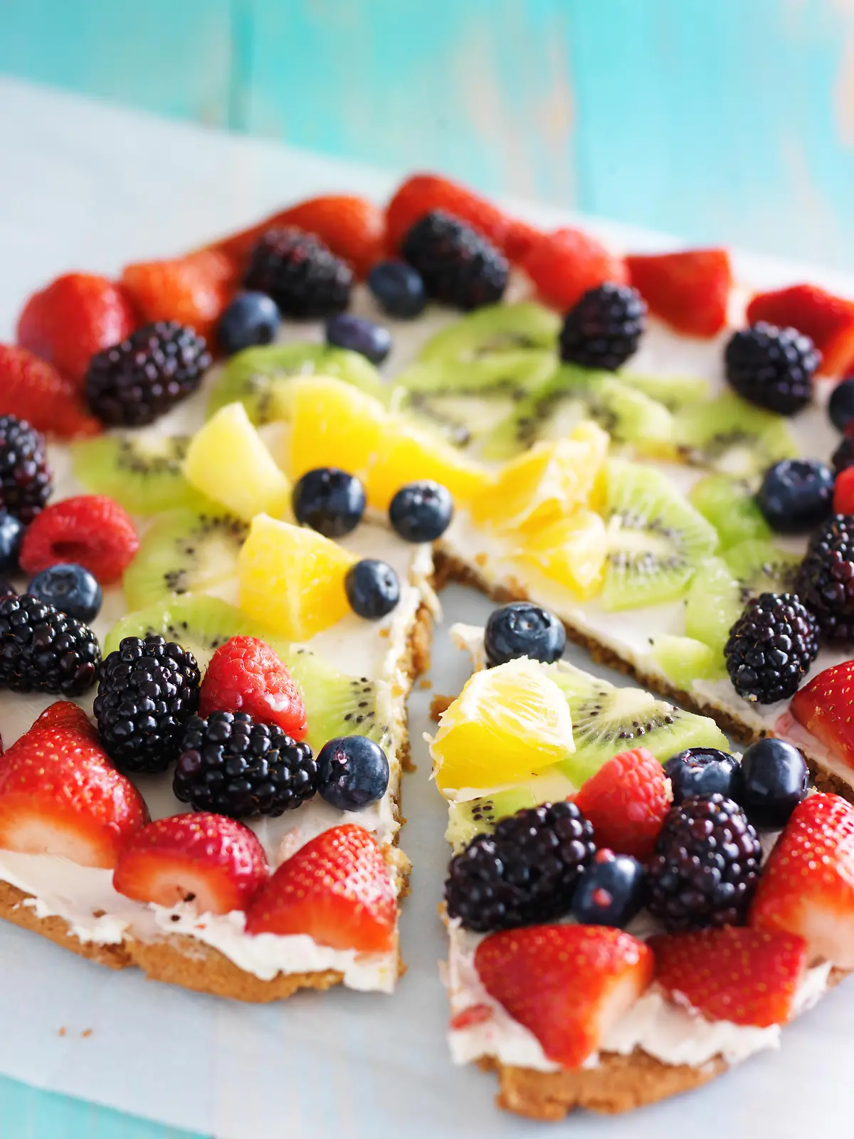colorful fruit pizza with berries and cream cheese on cookie crust