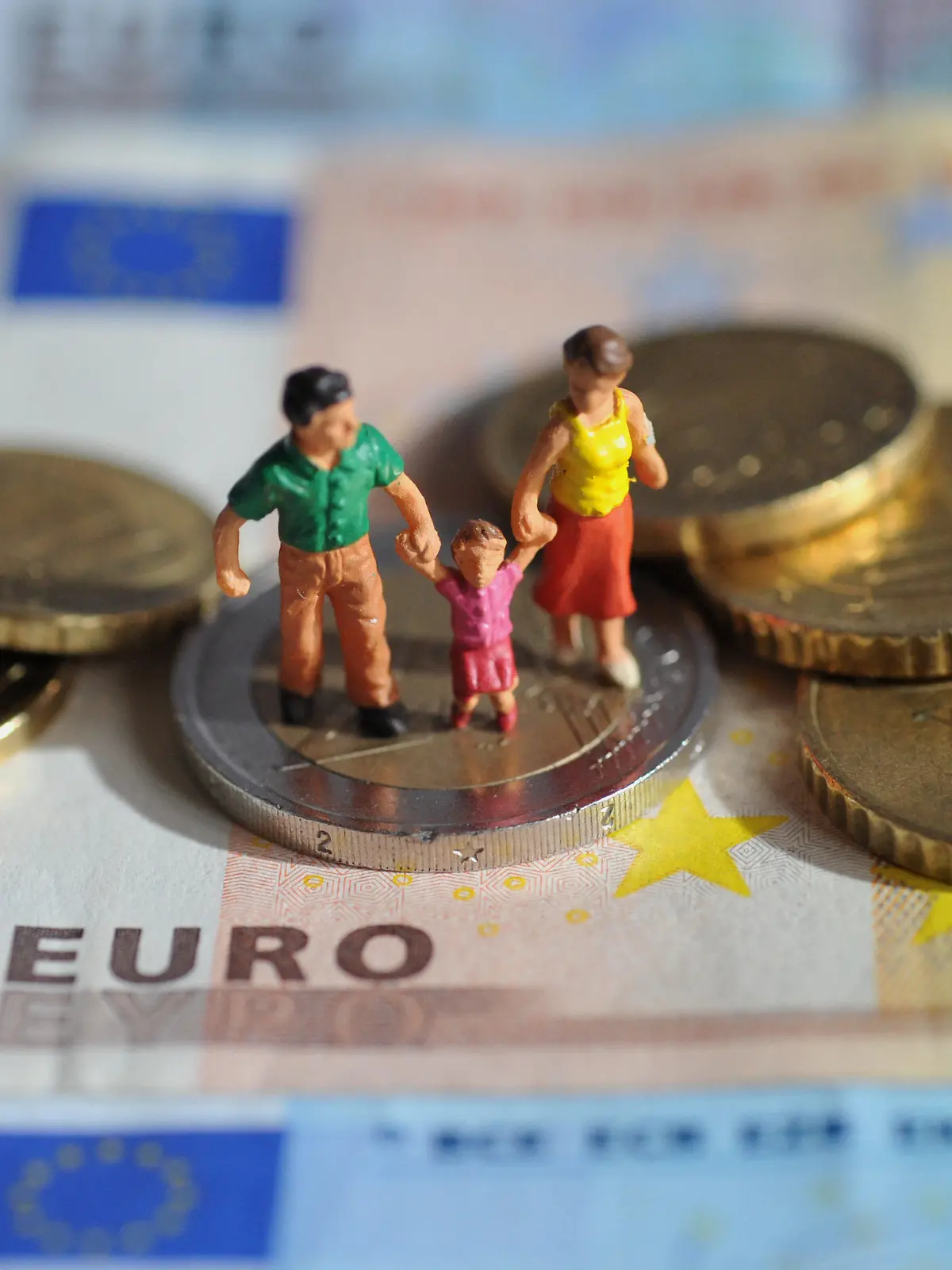 ARCHIV - ILLUSTRATION - Ein Paar mit einem Kind steht auf einer Zwei-Euro-Münze, die auf Geldscheinen liegt, aufgenommen am 16.02.2011. Wegen hoher Mietkosten rutschen einkommensschwache Familien laut einer Studie in vielen größeren deutschen Städten, wie zum Beispiel Frankfurt, unter Hartz-IV-Niveau. Foto: Andreas Gebert dpa (zu dpa/lhe "Studie: Nach Abzug der Miete viele arme Familien unter Hartz-IV" vom 22.07.2013) +++(c) dpa - Bildfunk+++