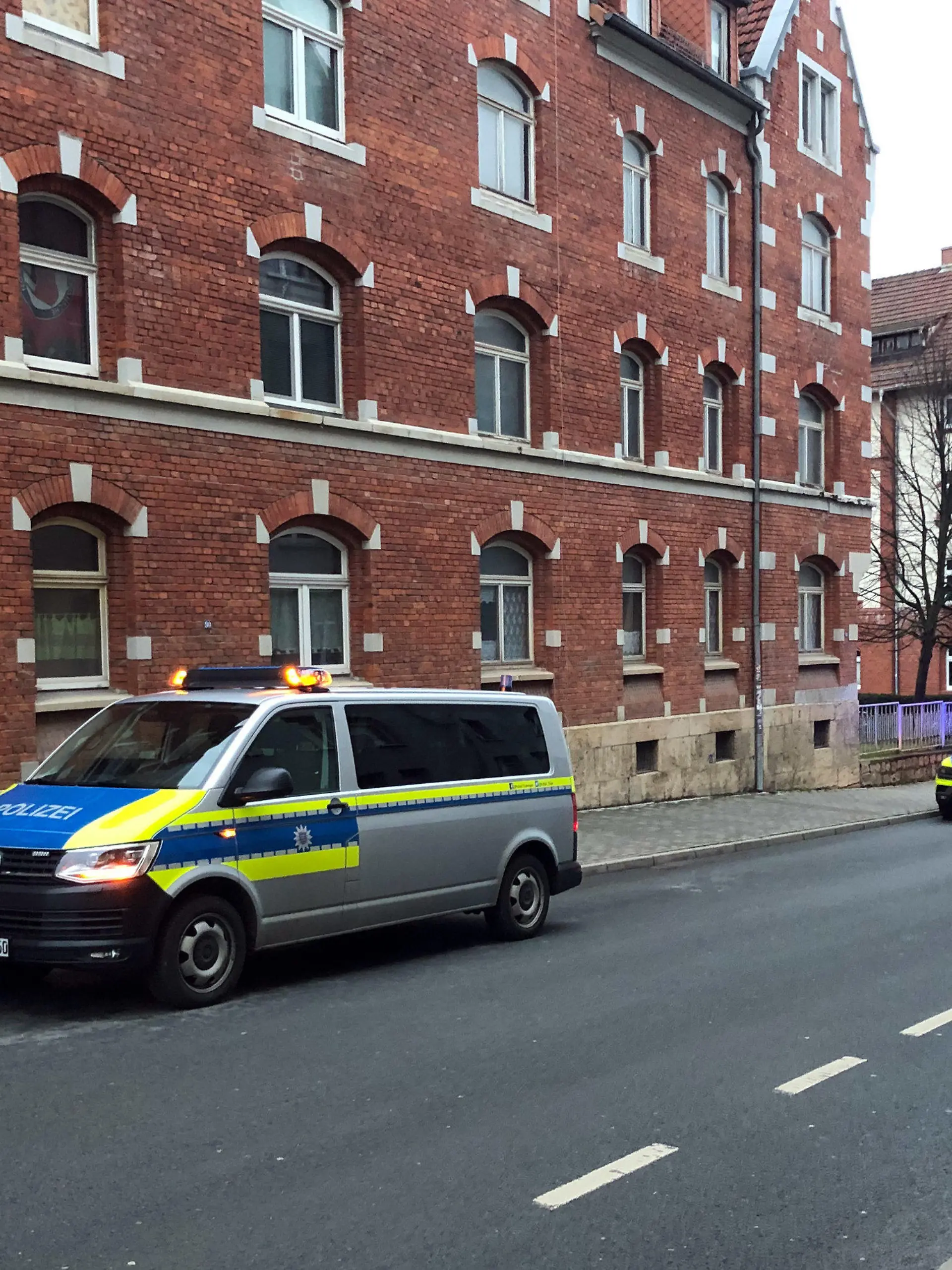 11.01.2022, Thüringen, Jena: Polizeifahrzeuge stehen vor einem Haus. Nach vermeintlichen Schüssen aus einem Luftgewehr auf Passanten ist die Polizei im Einsatz. Die Beamten klärten im Moment vor Ort, von wo aus die Schüsse hätten abgegeben werden können, sagte ein Sprecher der Landeseinsatzzentrale am Dienstag. Derzeit deute alles auf ein Luftgewehr hin. Zu möglichen Verletzten machte er vorerst keine Angaben. Es gebe aber keinen größeren Grund zur Besorgnis. Spezialkräfte, wie es in sozialen Medien berichtet worden war, seien nicht im Einsatz. Foto: David Hutzler/dpa +++ dpa-Bildfunk +++
