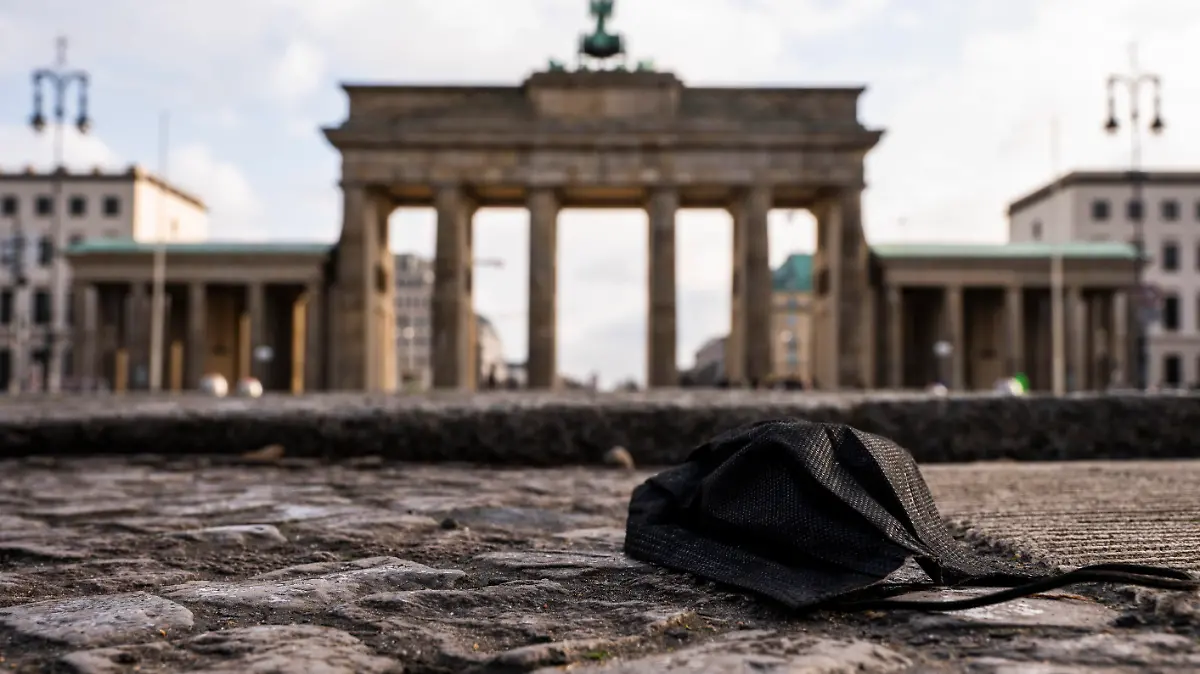 11.02.2022, Berlin: Eine schwarze Corona-Makse liegt auf dem Boden vor dem Brandenburger Tor. Foto: Christophe Gateau/dpa +++ dpa-Bildfunk +++