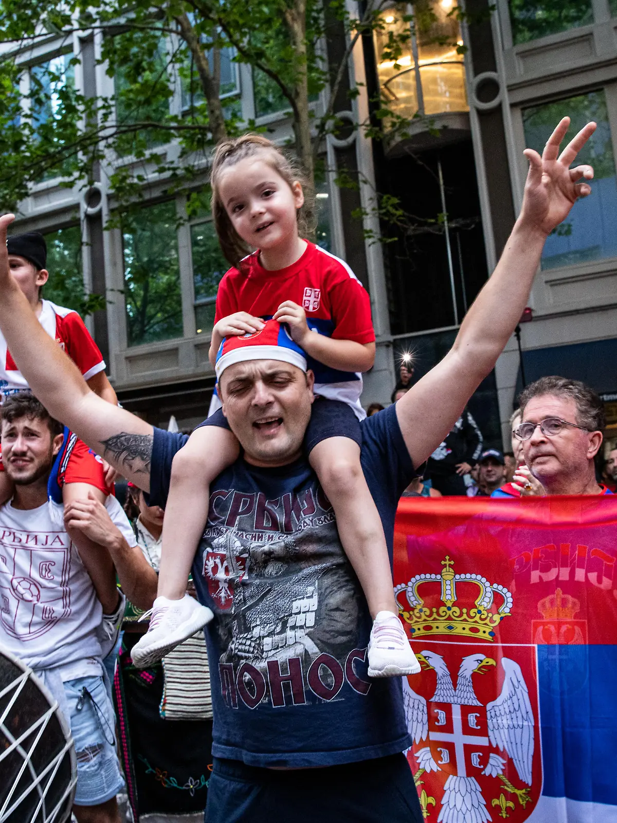 MELBOURNE, AUSTRALIA - JANUARY 10: Serbian tennis fans celebrate at Collins Street as they wait for Djokovic to leave on January 10, 2022 in Melbourne, Australia. Djokovic is in a detention hotel in Melbourne after his visa was cancelled on arrival to Australia last week. Djokovic filed a court challenge to the decision that will be heard in federal family and circuit court today. Djokovic is in Australia to play in the Australian Open which begins on January 17. (Photo by Diego Fedele/Getty Images)