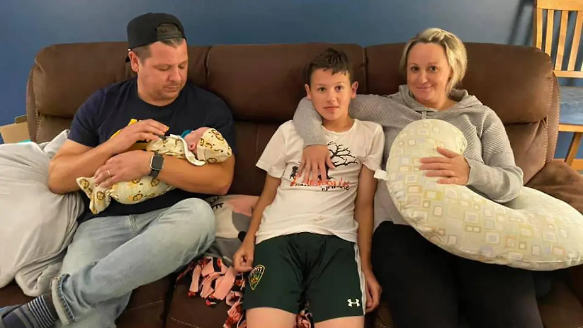 Story from Jam Press (Birth Complication)

Pictured: Tim, Michael and Jamie with Michael's 14 year old brother.

Emotional mum meets week-old baby for first time after amniotic fluid leaked into her blood during birth and caused 'explosion in her chest'.

This is the emotional moment a mum met her week-old baby for the first time after her amniotic fluid leaked into her bloodstream and left her fighting for her life.

Jamie Miller, 39, from Illinois, USA, suffered an amniotic fluid embolism - a very rare birth complication that can be fatal for both mum and baby.

But miraculously, both Jamie and baby Michael survived and are now thriving at home.

“I know it is pretty much a miracle that both of us survived with likely no physical effects,” Jamie told Jam Press.

“I am very aware of how rare the event was and then how rare it is that we both are here to talk about it.”

As a nurse who had previously worked on the delivery unit where she gave birth, Jamie had learned about the dangers of AFE throughout her career, but hoped she would never see it and never expected to experience it herself.

Although she was at a slightly higher risk of complications because of her age, she had a normal pregnancy and continued to work right up until the day before her induction and labour.

Welcoming a new baby was particularly special for Jamie and husband Tim, 38, after losing their daughter three and a half years ago.

Jamie said: “Our family has been through a lot. My daughter was diagnosed with Stage IV neuroblastoma at the age of six. She died 11 months later from complications related to her treatment.

“We are still healing and think about her constantly. We were prepared for an emotional pregnancy and birth knowing that this brother will never get to meet his amazing sister.

“We thought that was going to be the hardest part. We were not prepared for what happened. Anyone who has a child after losing one knows that the emotions are very complicated. You miss t