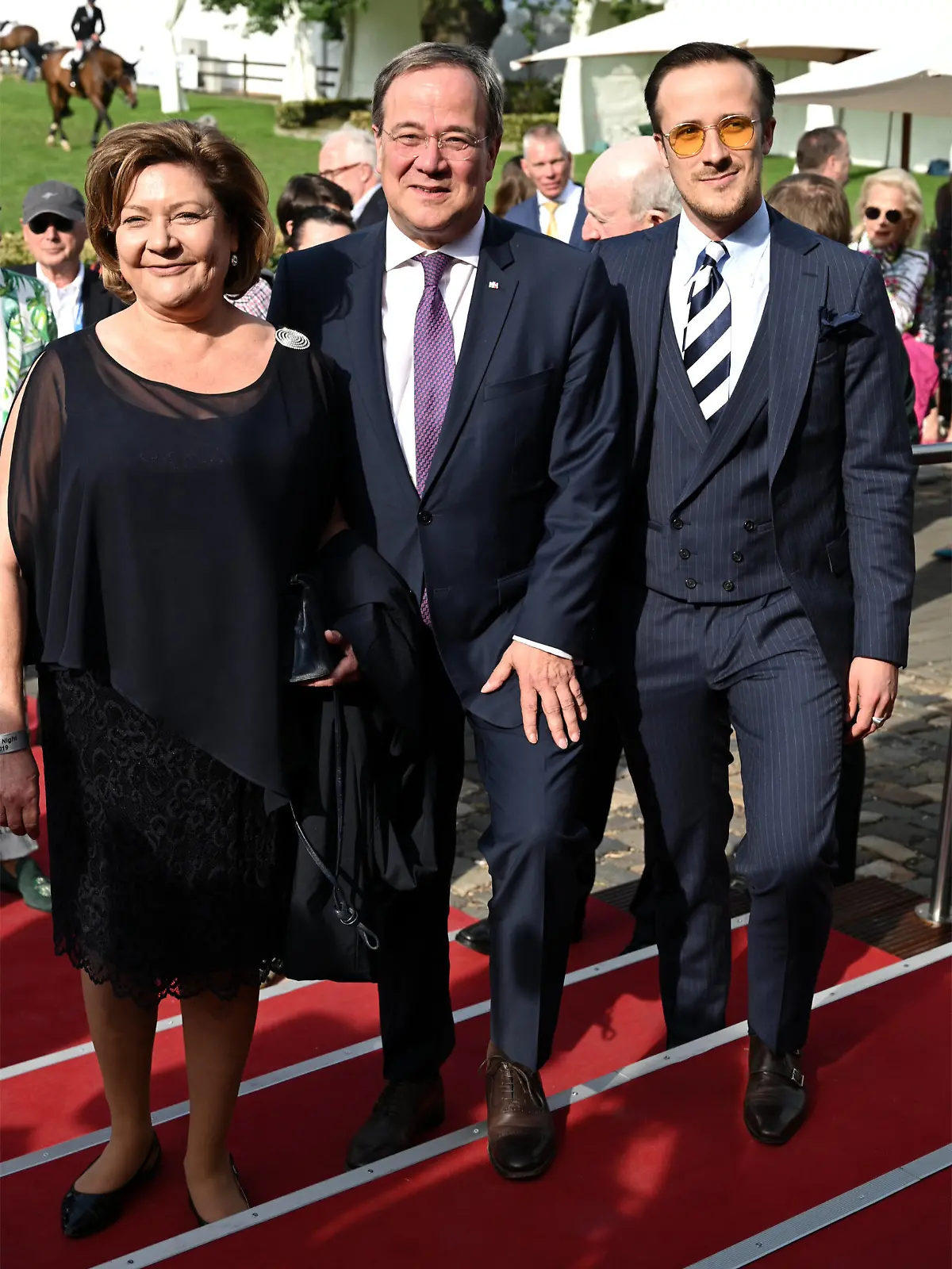 ARCHIV - 16.07.2019, Nordrhein-Westfalen, Köln: Der Ministerpräsident von Nordrhein-Westfalen, Armin Laschet (M, CDU), seine Frau Susanne Laschet (l) und Sohn Johannes Laschet bei der MediaNight beim Reittunier CHIO 2019. Johannes «Joe» Laschet hatte dem Mode-Unternehmen van Laack den Kontakt zu seinem Vater hergestellt, als zu Beginn der Pandemie Masken-Produzenten gesucht wurden (zu dpa: «NRW kauft van Laack-Masken: SPD hat Fragen zur Rolle von Laschet-Sohn») Foto: Henning Kaiser/dpa +++ dpa-Bildfunk +++