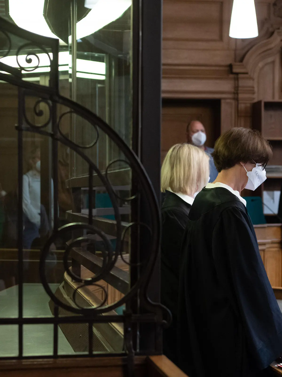 10.08.2021, Berlin: Der Angeklagte (l) sitzt in einem Gerichtssaal und hält sich eine Pappe vor dem Gesicht. Der 41 Jahre alte Lehrer muss sich wegen mutmaßlichem Mord verantworten. Der Beschuldigte soll einen 43-jährigen Mann, den er kurz zuvor über ein Dating-Portal kennengelernt hatte, in seiner Wohnung getötet haben. Dann soll er das Opfer zerteilt und die Leichenteile an verschiedenen Orten in Berlin abgelegt haben. Die Staatsanwaltschaft geht von einer "sadistisch-kannibalistisch geprägten sexuellen Tatmotivation" aus. Foto: Paul Zinken/dpa +++ dpa-Bildfunk +++
