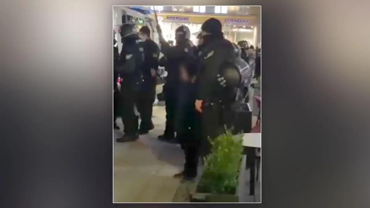 Ein kleiner Junge steht inmitten von Polizeibeamten auf einer Corona-Demo in München.