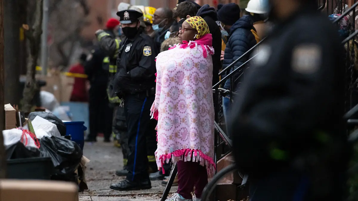 21.08.2020, USA, Philadelphia: Umstehende und Polizisten beobachten den Einsatz der Feuerwehr von Philadelphia bei einem tödlichen Reihenhausbrand. Der Brand hat zu mehreren Todesopfern geführt. Foto: Alejandro A. Alvarez/The Philadelphia Inquirer/dpa - ACHTUNG: Nur zur redaktionellen Verwendung und nur mit vollständiger Nennung des vorstehenden Credits +++ dpa-Bildfunk +++