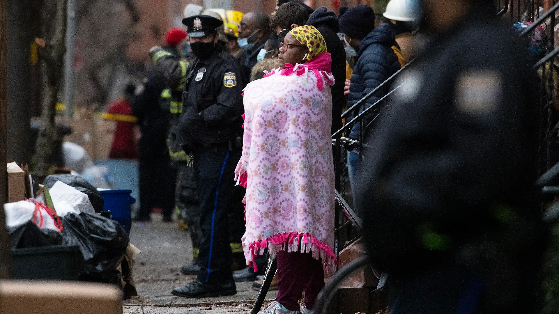 21.08.2020, USA, Philadelphia: Umstehende und Polizisten beobachten den Einsatz der Feuerwehr von Philadelphia bei einem tödlichen Reihenhausbrand. Der Brand hat zu mehreren Todesopfern geführt. Foto: Alejandro A. Alvarez/The Philadelphia Inquirer/dpa - ACHTUNG: Nur zur redaktionellen Verwendung und nur mit vollständiger Nennung des vorstehenden Credits +++ dpa-Bildfunk +++