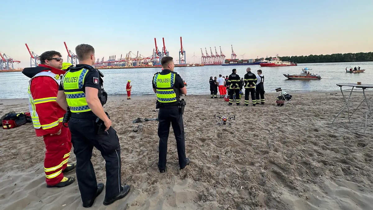 05.06.2023, Hamburg: Rettungskräfte und Polizei sind am Hamburger Elbstrand im Einsatz. Polizei und Feuerwehr haben in Hamburg bis zum späten Montagabend nach einem Menschen in der Elbe gesucht. Augenzeugen hätten beobachtet, wie ein Mann kurz vor 20.00 Uhr vom Elbstrand aus ins Wasser gegangen und plötzlich untergegangen sei, sagte ein Sprecher der Polizei. Eine Person versuchte demnach noch vergeblich, dem Vermissten hinterherzuschwimmen und ihn zu retten. Neben zahlreichen Einsatzkräften von Polizei, Feuerwehr und DLRG waren Taucher sowie zwei Hubschrauber mit Wärmebildkameras nahe des bekannten Restaurants Strandperle im Einsatz. Bis zum späten Abend blieb die Suche erfolglos. Foto: Steven Hutchings/dpa +++ dpa-Bildfunk +++