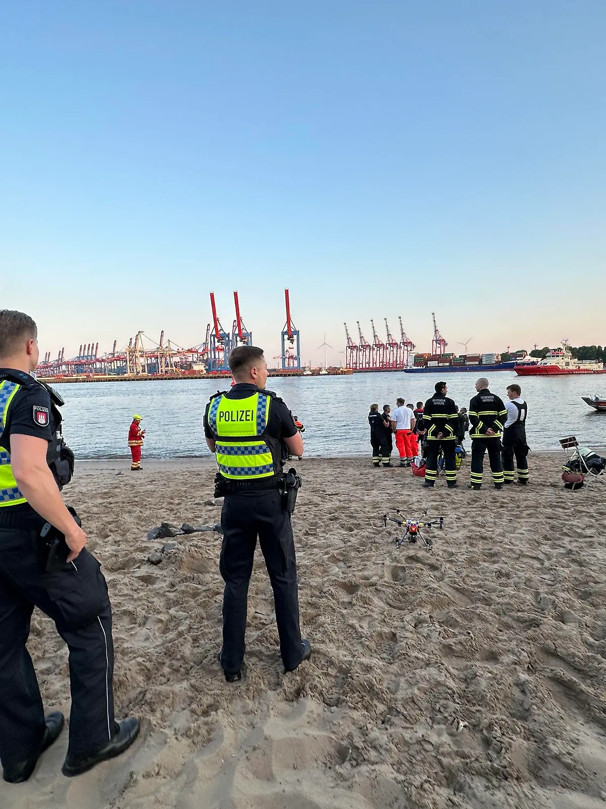 05.06.2023, Hamburg: Rettungskräfte und Polizei sind am Hamburger Elbstrand im Einsatz. Polizei und Feuerwehr haben in Hamburg bis zum späten Montagabend nach einem Menschen in der Elbe gesucht. Augenzeugen hätten beobachtet, wie ein Mann kurz vor 20.00 Uhr vom Elbstrand aus ins Wasser gegangen und plötzlich untergegangen sei, sagte ein Sprecher der Polizei. Eine Person versuchte demnach noch vergeblich, dem Vermissten hinterherzuschwimmen und ihn zu retten. Neben zahlreichen Einsatzkräften von Polizei, Feuerwehr und DLRG waren Taucher sowie zwei Hubschrauber mit Wärmebildkameras nahe des bekannten Restaurants Strandperle im Einsatz. Bis zum späten Abend blieb die Suche erfolglos. Foto: Steven Hutchings/dpa +++ dpa-Bildfunk +++