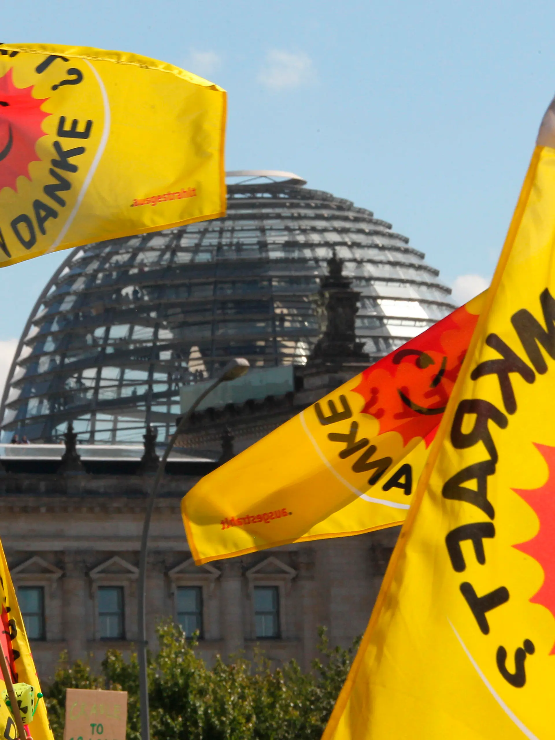 Fahnen von Atomkraft-Gegnern, die am Kanzleramt in Berlin gegen die Atompolitik der Bunderegierung demonstrieren, wehen am Sonntag (05.09.2010) vor der Kuppel des Reichstages. Die Spitzen der Koalition unter Leitung von Bundeskanzlerin Merkel treffen sich hier zu einem Gespräch über Energiepolitik. Thema des Treffens ist die Laufzeitverlängerung von Atomkraftwerken in Deutschland. Foto: Wolfgang Kumm dpa/lbn  +++(c) dpa - Bildfunk+++