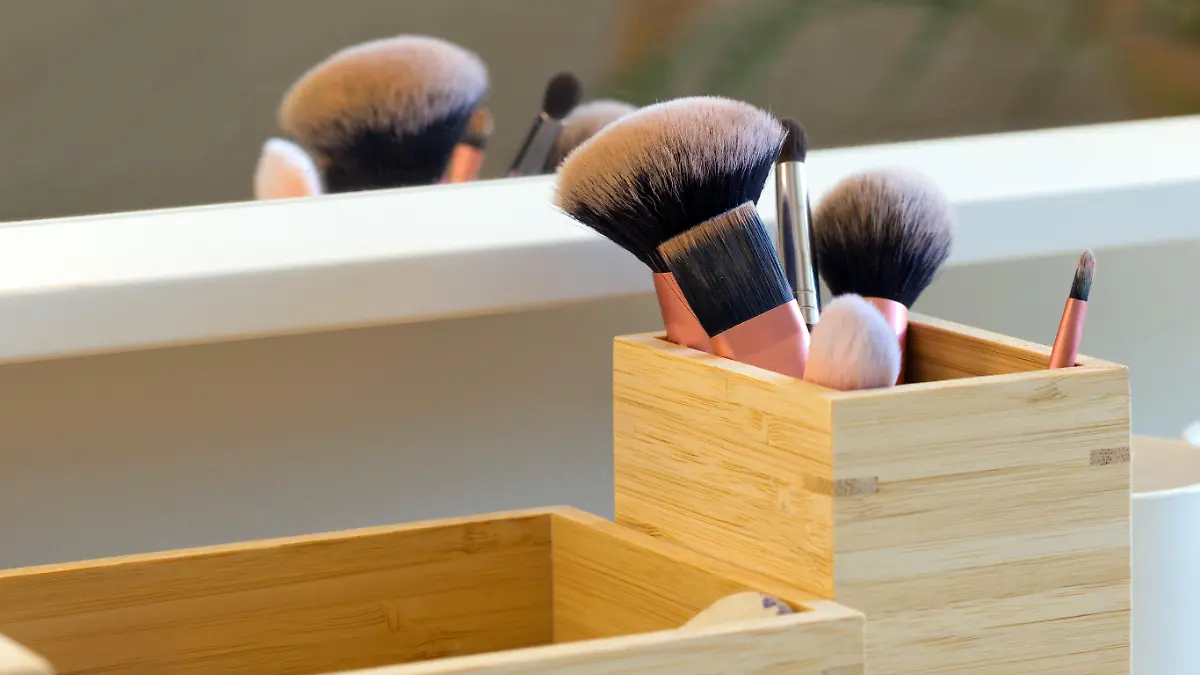 Professional makeup brush set on makeup table near mirror in wooden storage box close-up beauty concept