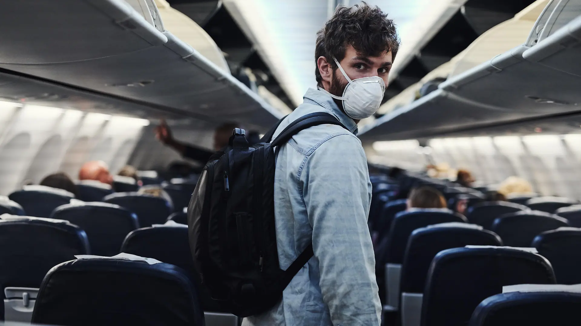 Shot of a young man wearing a mask and boarding an airplane