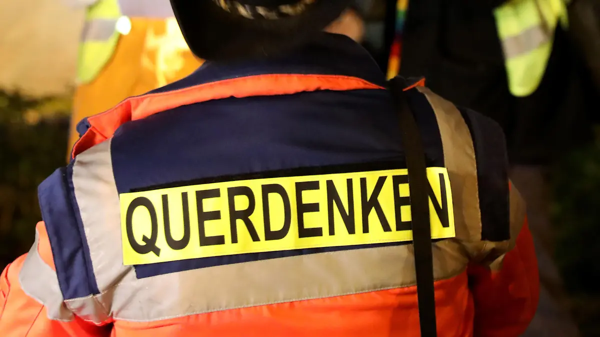 Das Wort «Querdenken» trägt ein Teilnehmer einer Demonstration gegen Corona-Maßnahmen auf dem Rücken während er den Organisatoren Jens Kaufmann (l) filmt. Auf dem Veranstaltungsgelände müssen die Demonstranten wegen des Coronavirus einen Mund-Nasenschutz tragen. Zudem gilt das Abstandsgebot. In mehreren Städten Deutschlands haben Menschen gegen die Corona-Maßnahmen demonstriert.